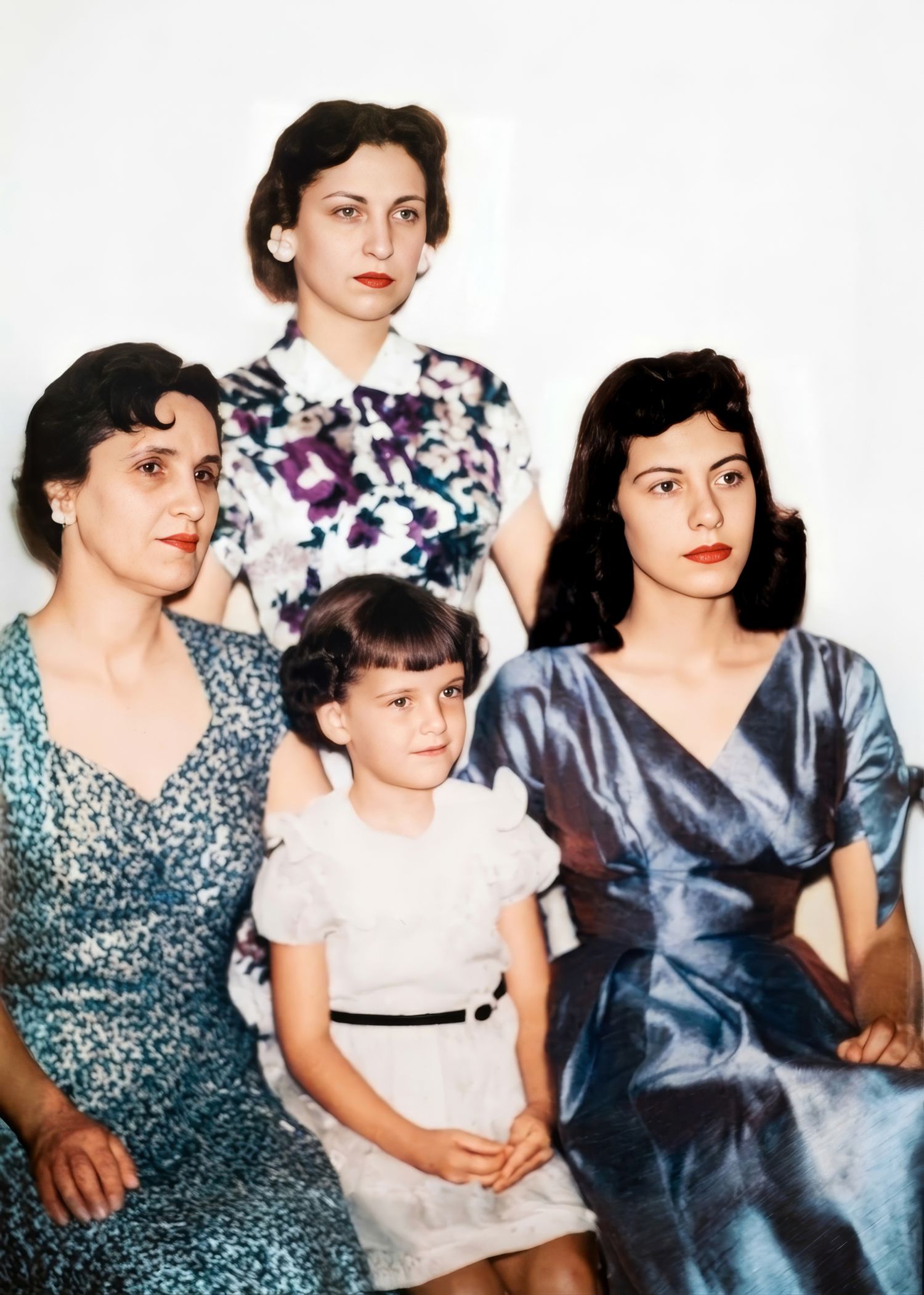 Restored colorized vintage photo of three women and a young girl in a formal family portrait.