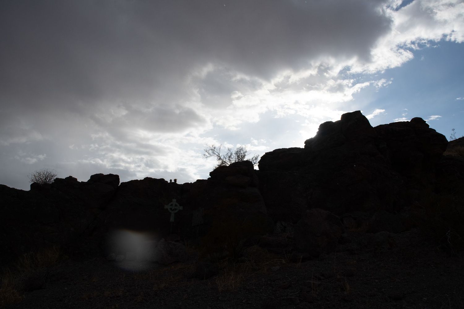 Dramatic silhouette of large desert boulders against a cloudy sky at dusk.