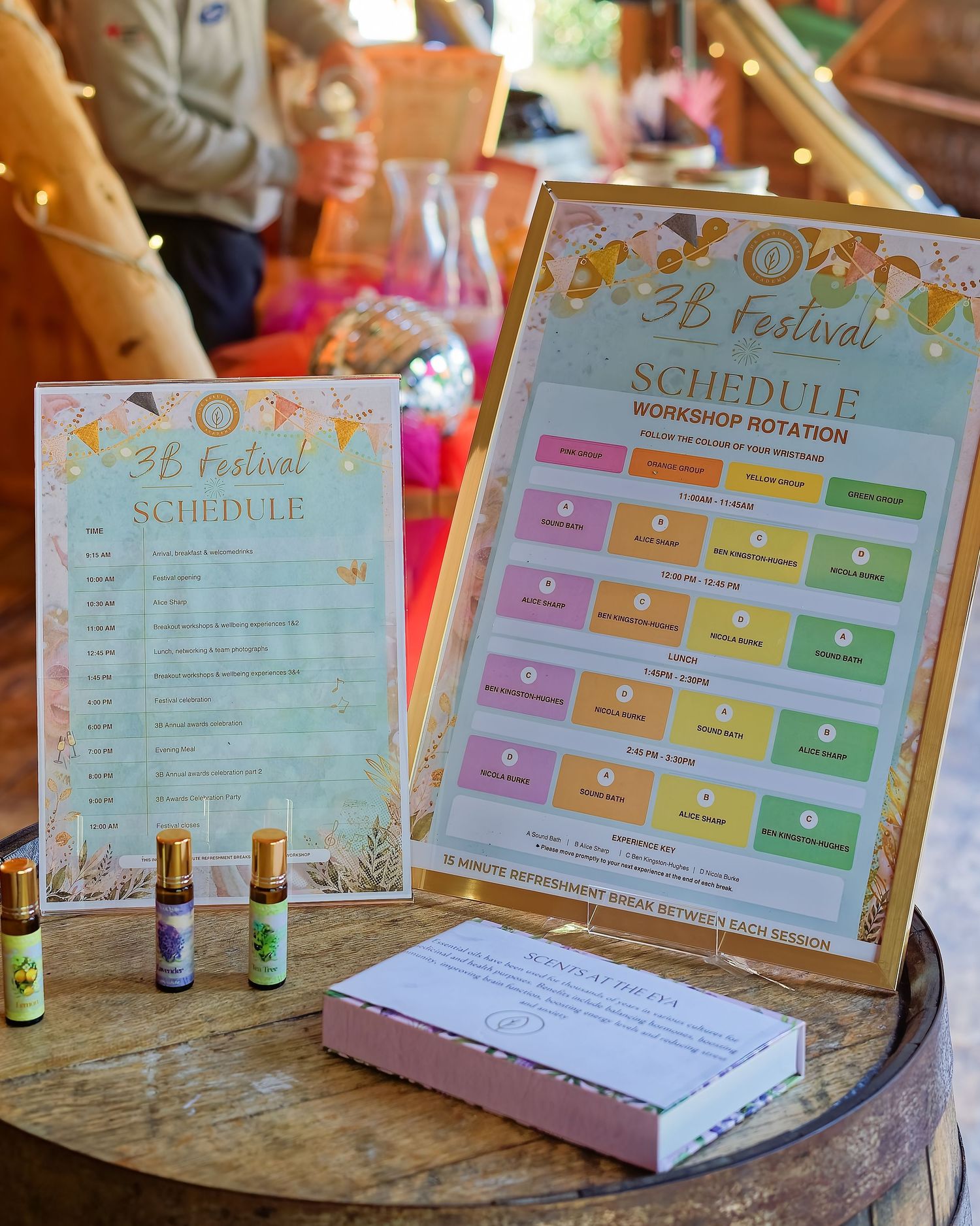 Colorful 3B Festival schedule and workshop rotation charts displayed on a barrel with essential oil bottles.