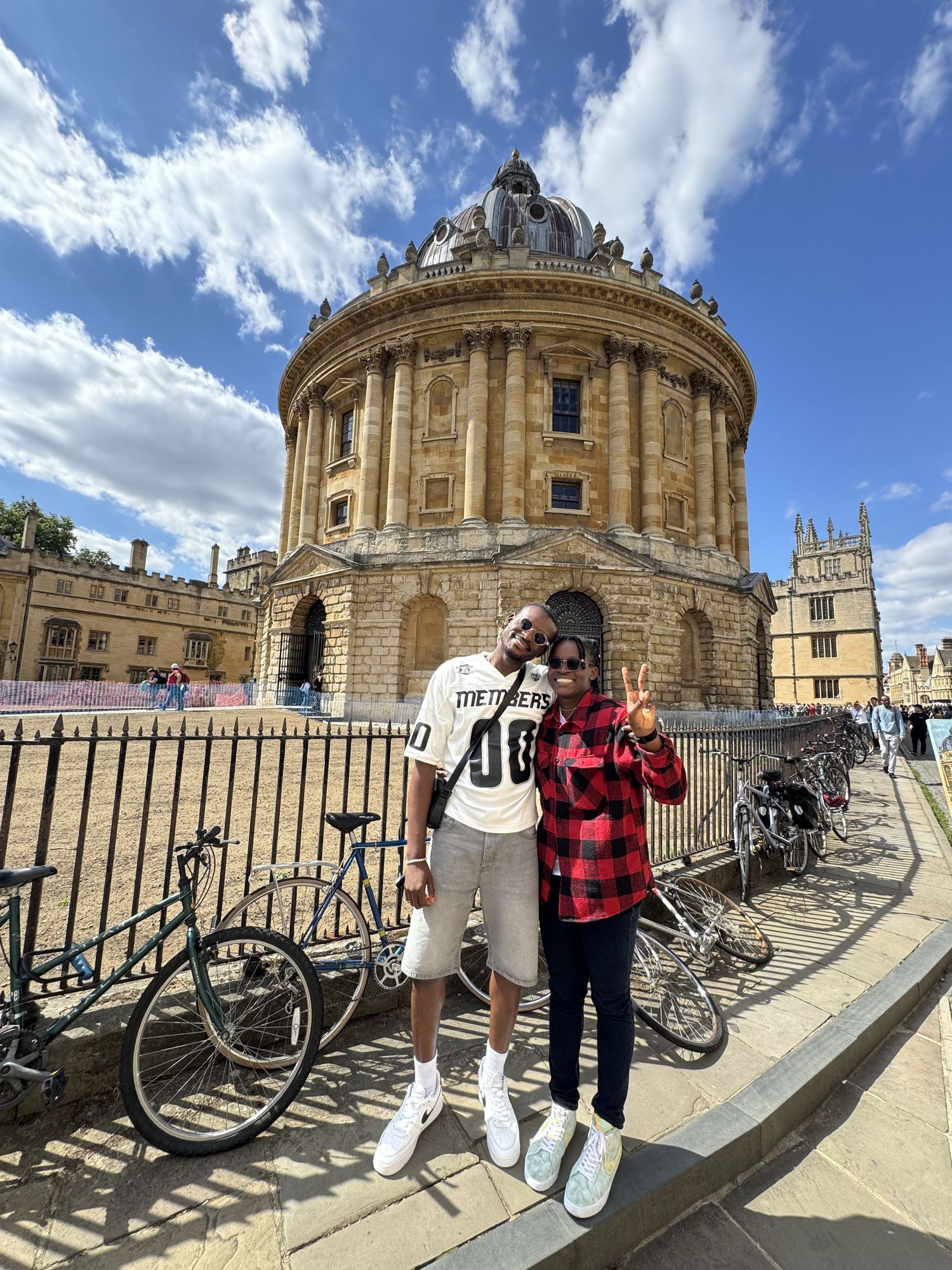 Couple posing in front of the historic Radcliffe Camera building in Oxford, England.