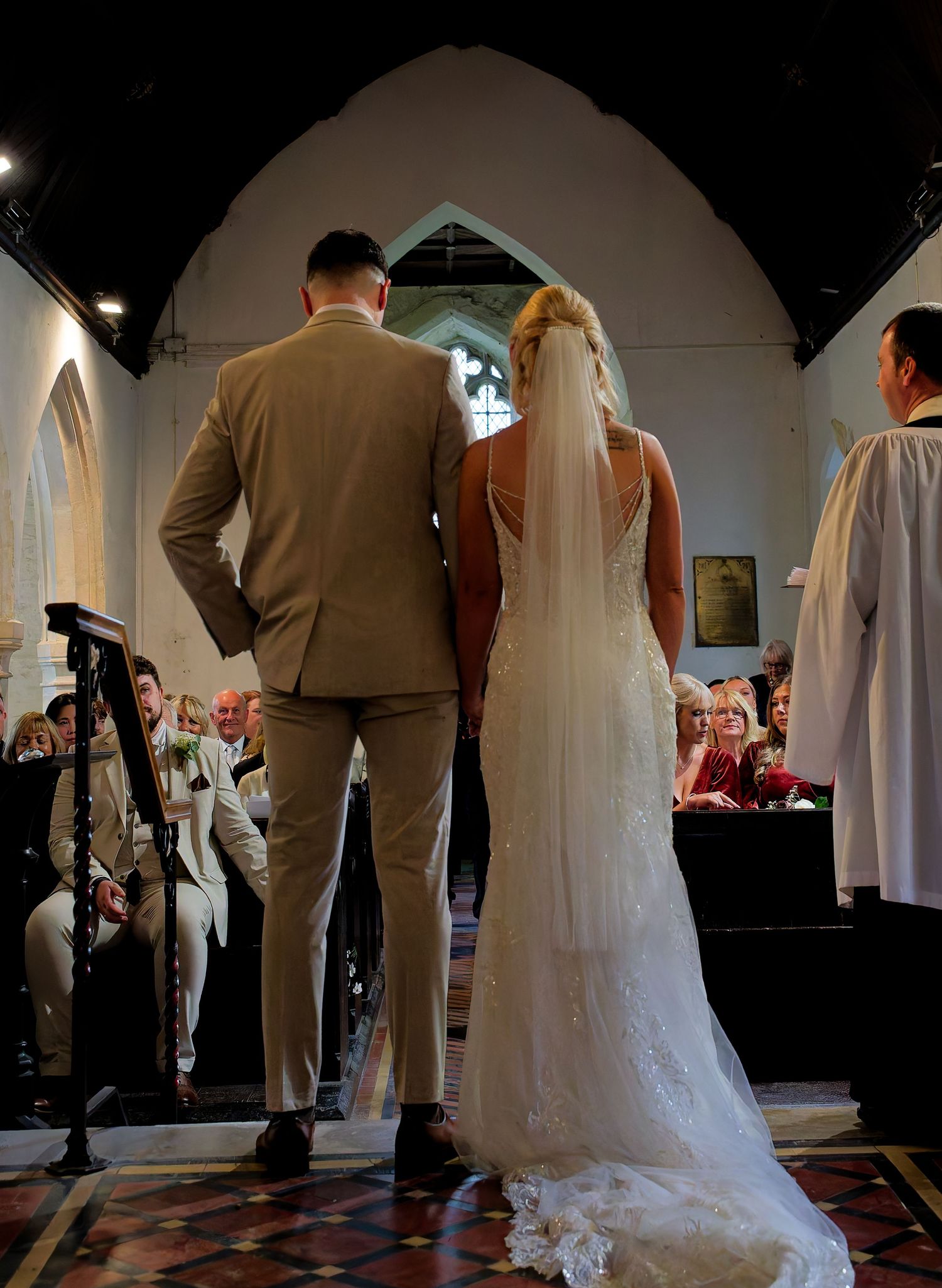 Bride and groom standing at the altar during a church wedding ceremony, viewed from behind.
