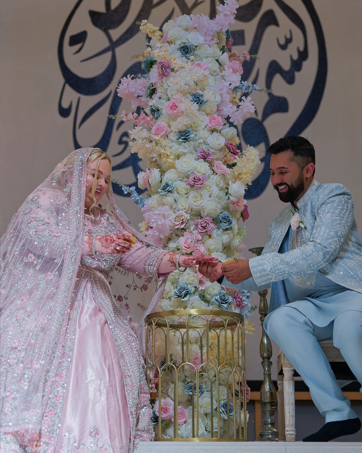 Bride and groom exchanging rings at an elegant wedding ceremony with floral tower backdrop.