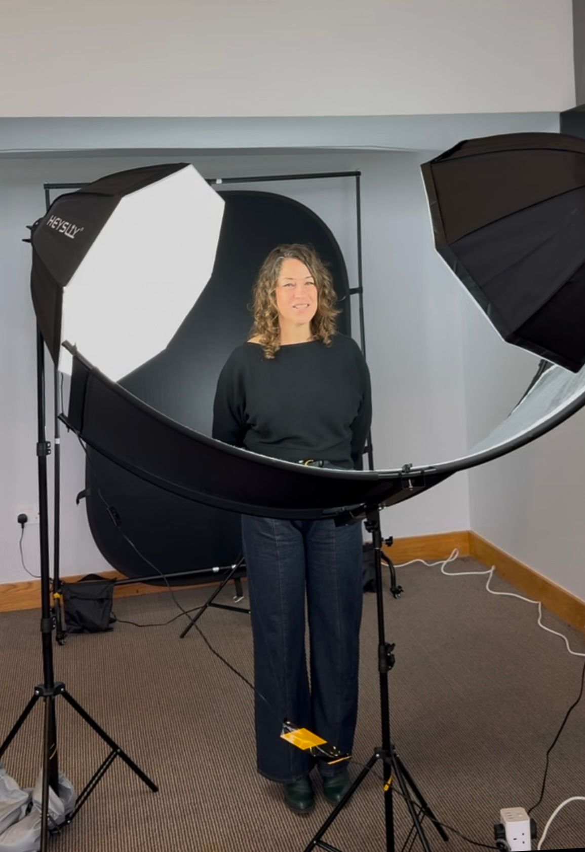 Behind the scenes photo shoot setup with lighting equipment and reflectors in studio.