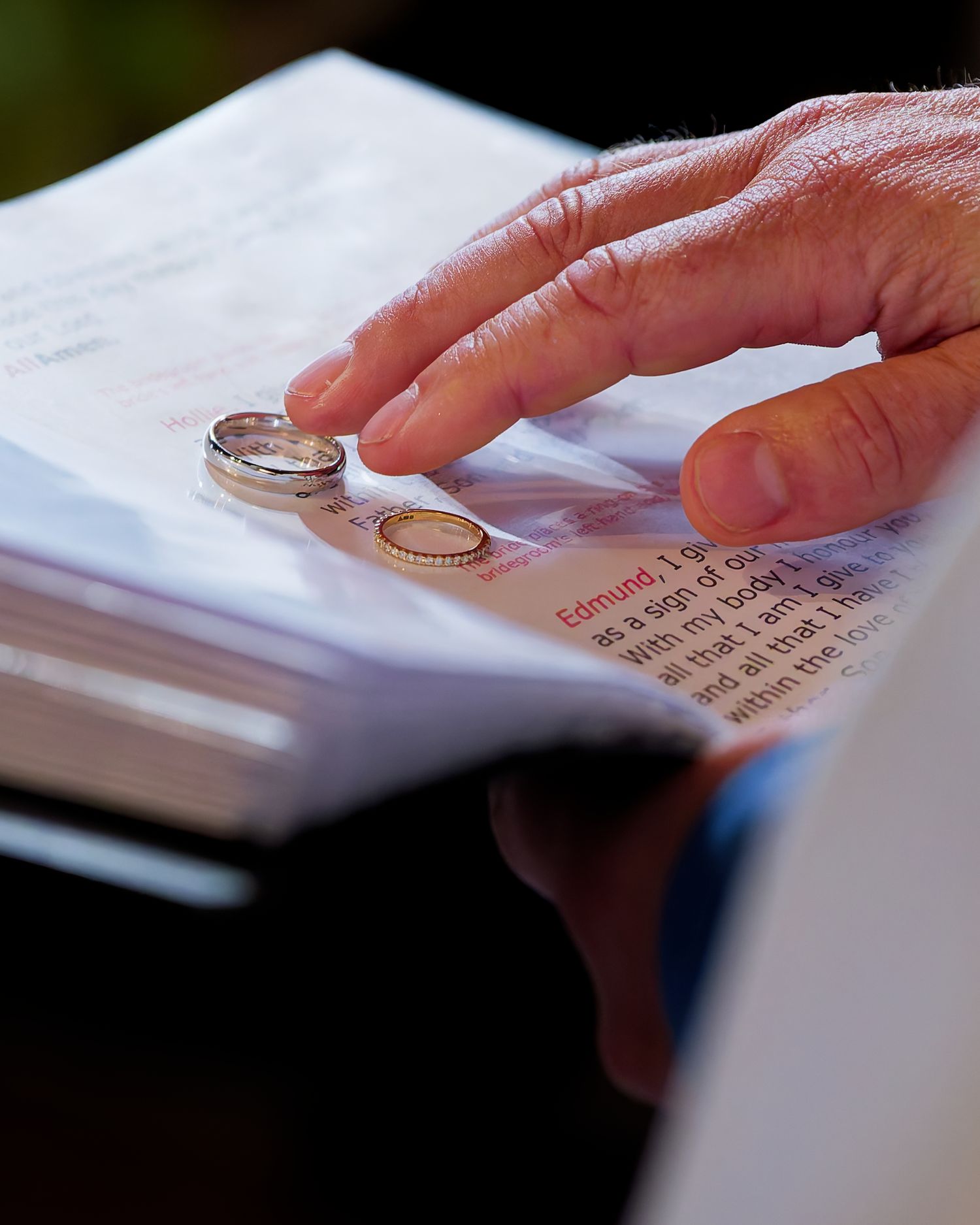 Wedding rings resting on an open Bible during a traditional ring ceremony exchange.