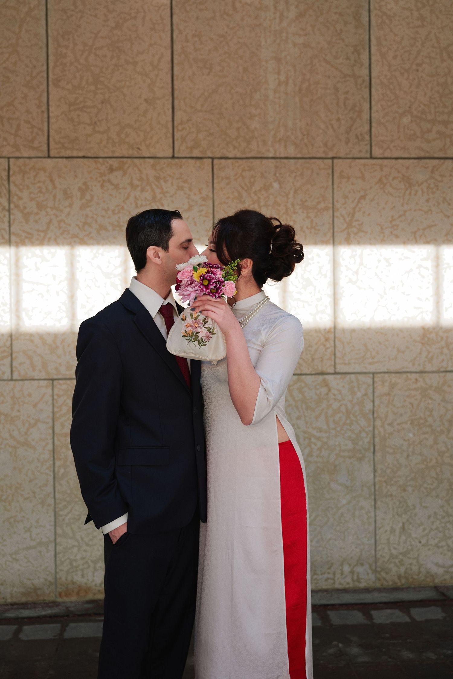 Bride and groom sharing a kiss by the window with a bridal bouquet, Winnipeg wedding