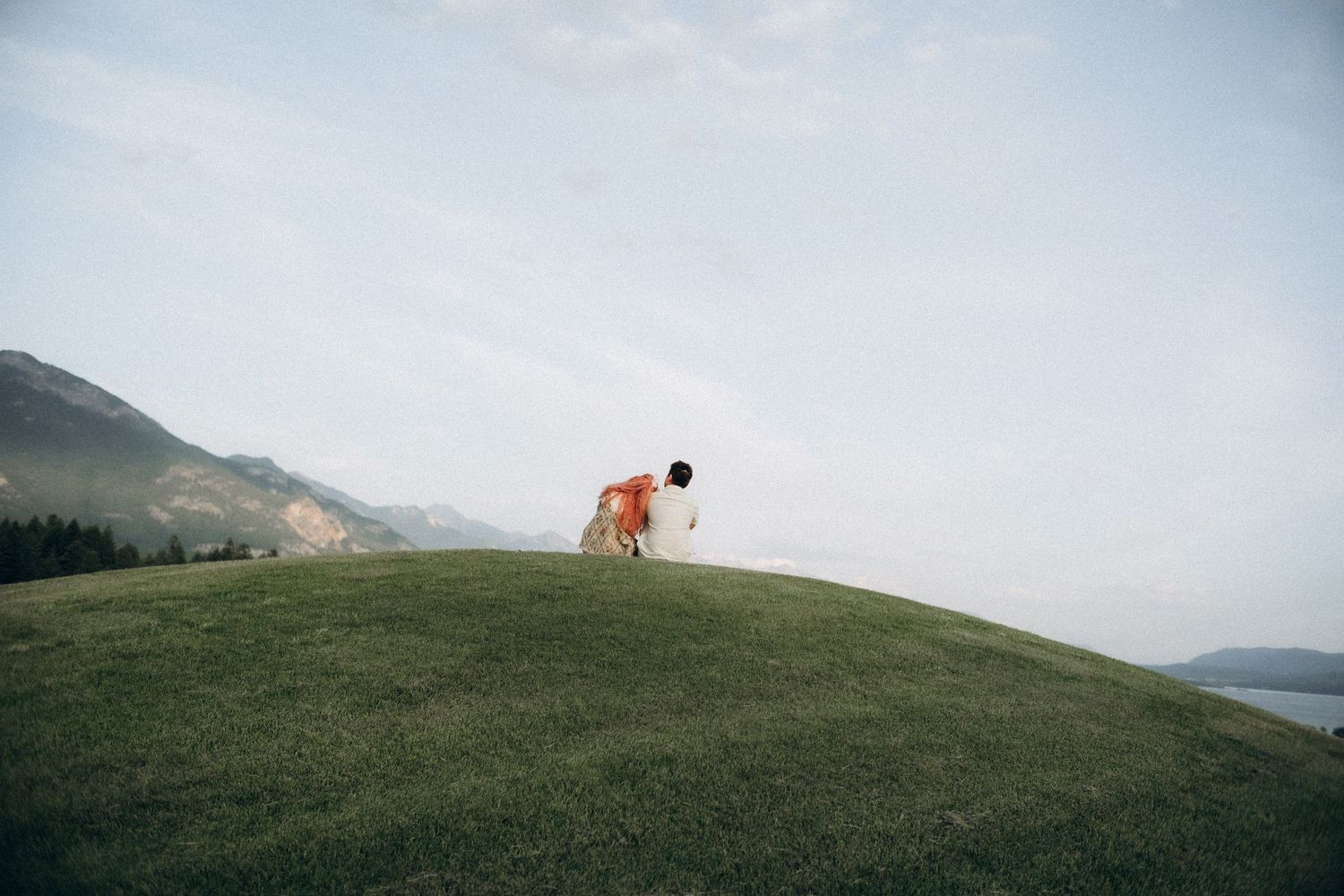 Couple embracing by the lake at sunset during their engagement session