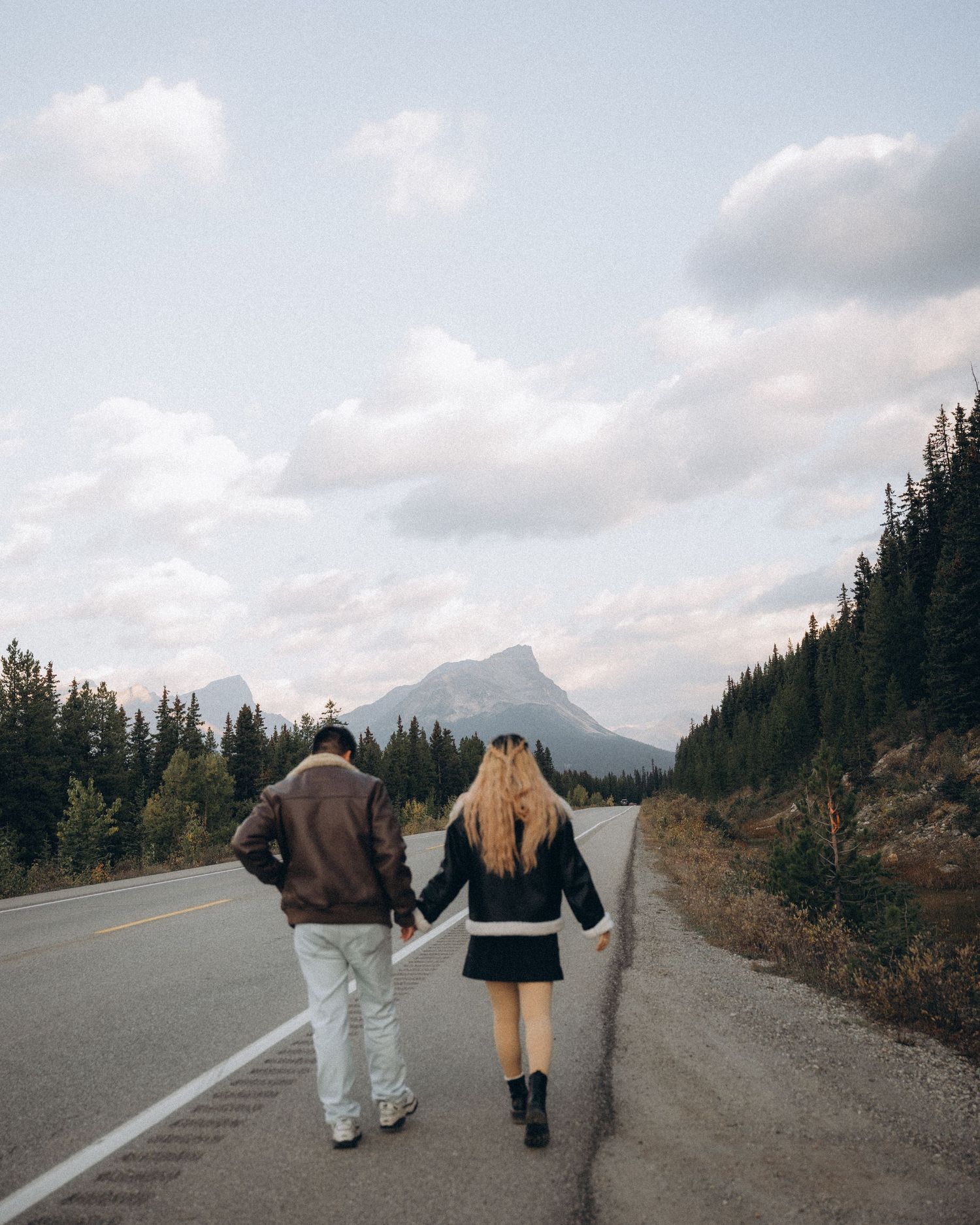 Couple walking hand in hand on a mountain road during their engagement session