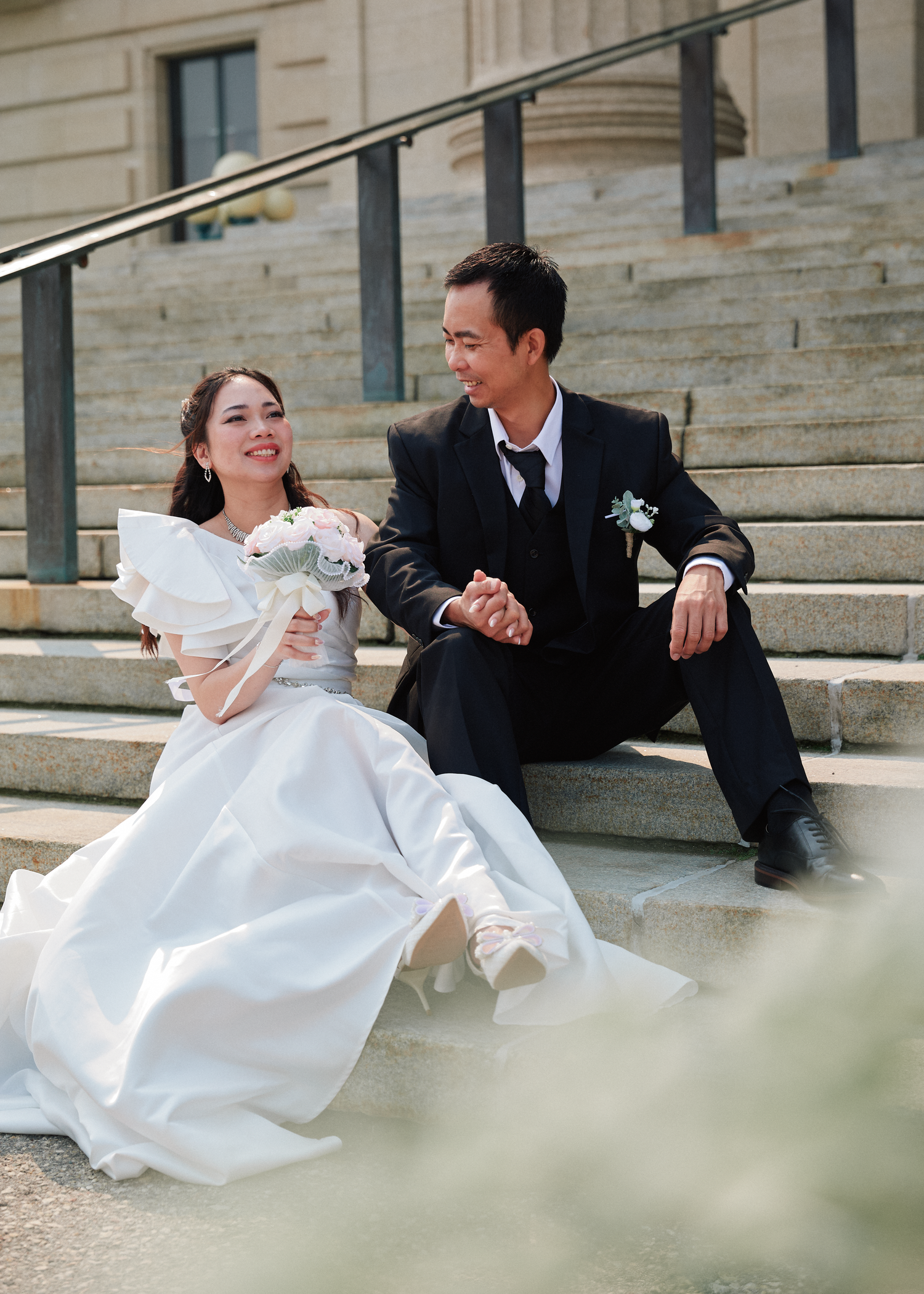 Bride and groom sitting on outdoor steps after their Winnipeg wedding ceremony