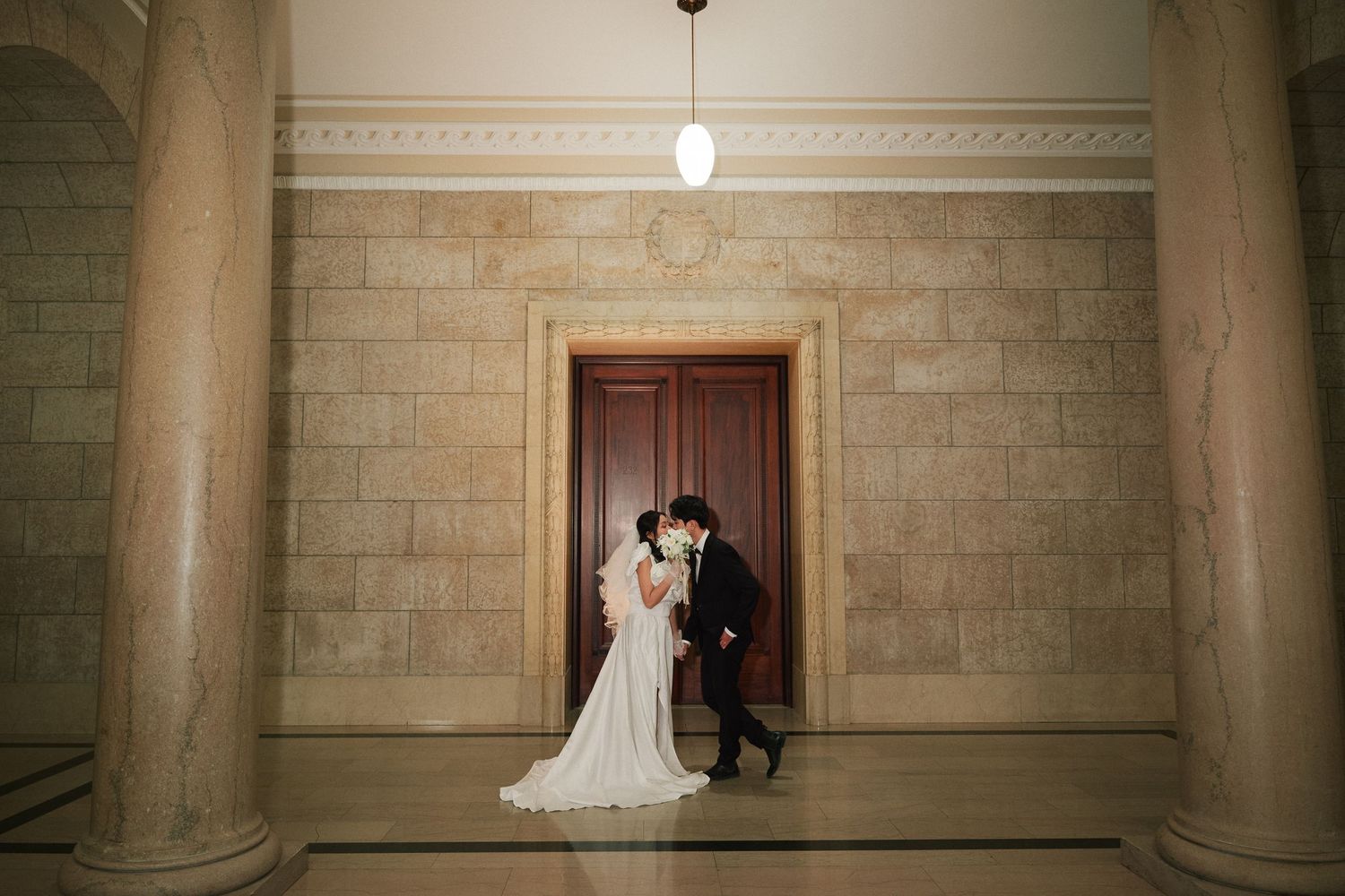 Bride and groom in front of ornate wooden doors at the Manitoba Legislative Building Winnipeg