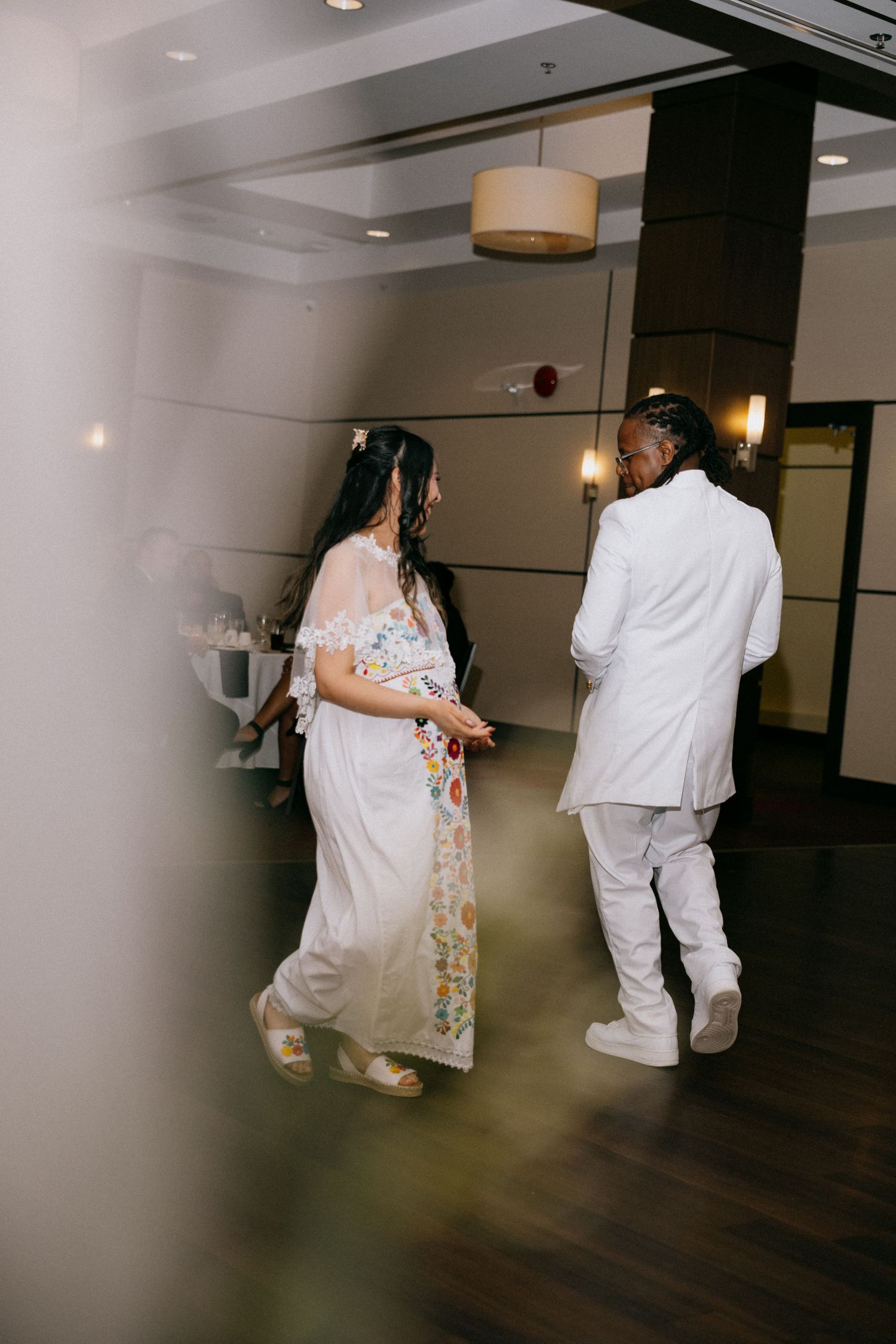 Bride and groom in white walking through the venue hallway in Winnipeg