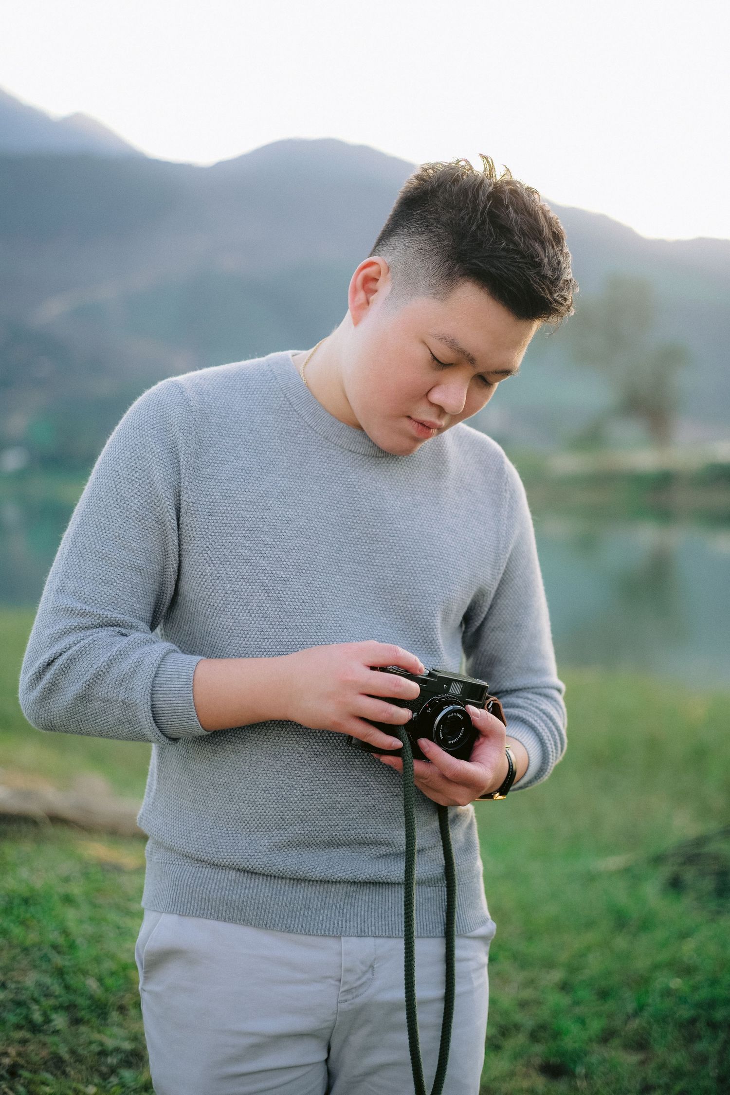 Darin Nguyen, Winnipeg wedding photographer, holding a film camera outdoors