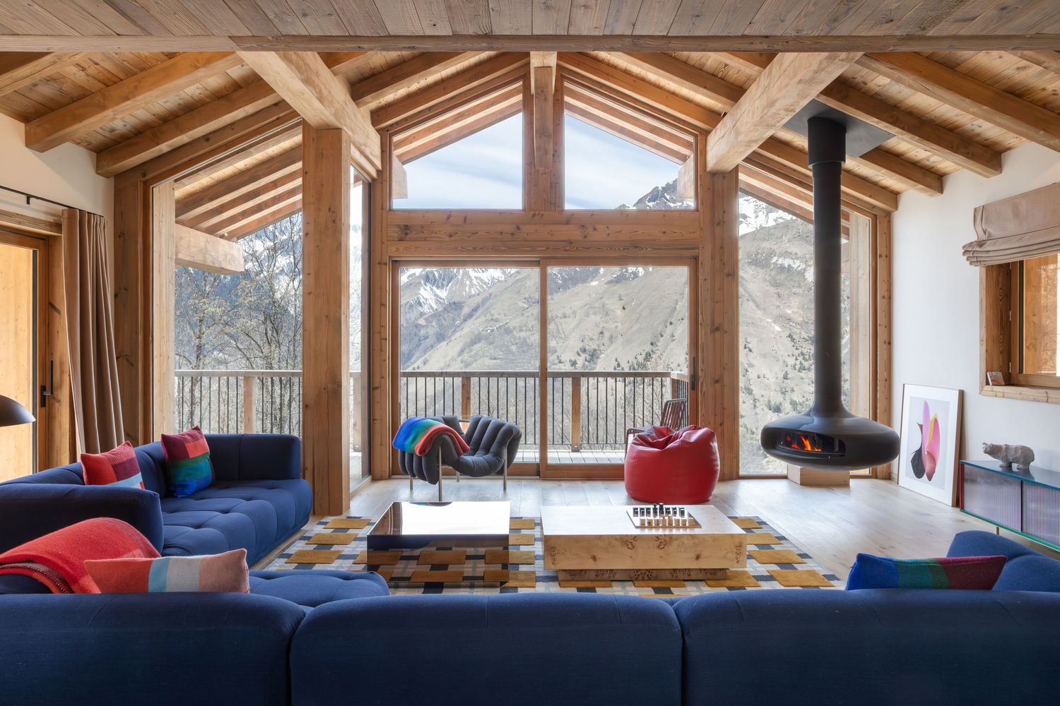 large contemporary living space with large blue sofas and floor to ceiling windows overlooking snowy mountains