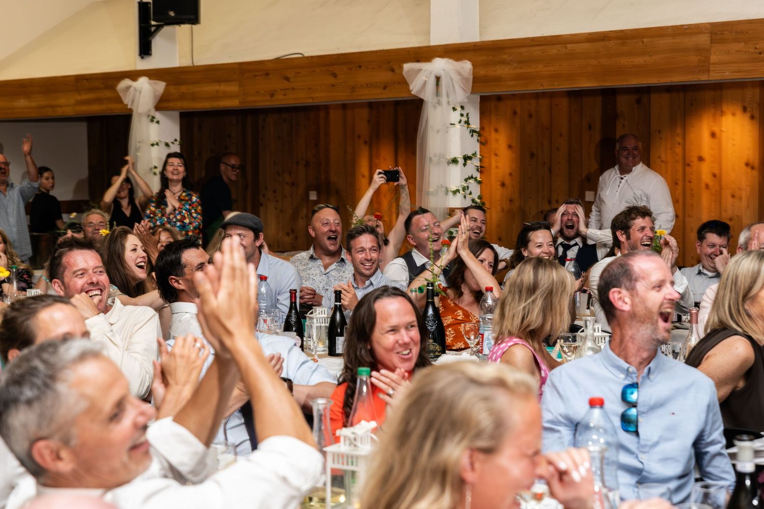 crowd cheers and waves hands during wedding reception