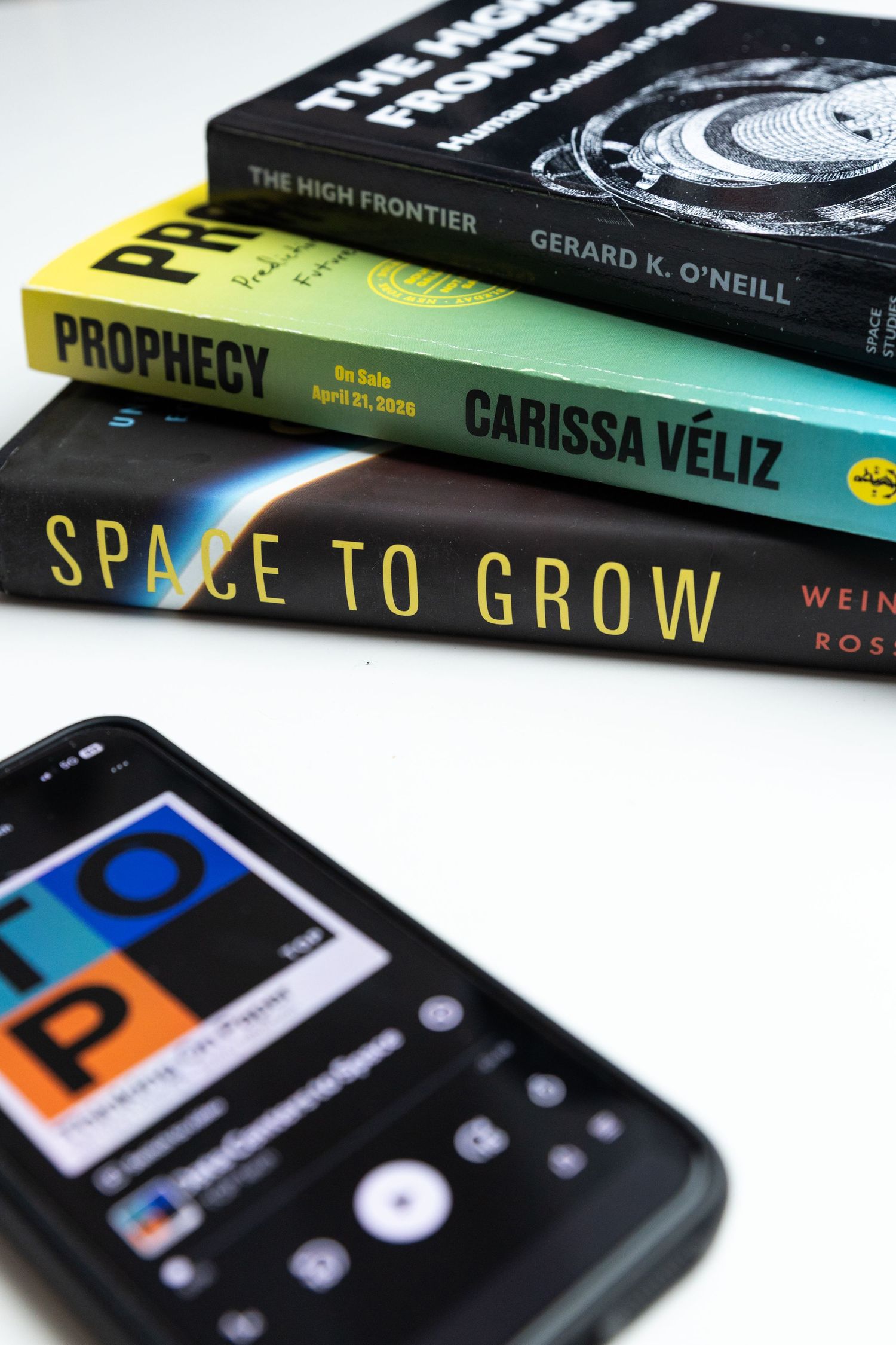 phone with podcast displayed next to pile of books