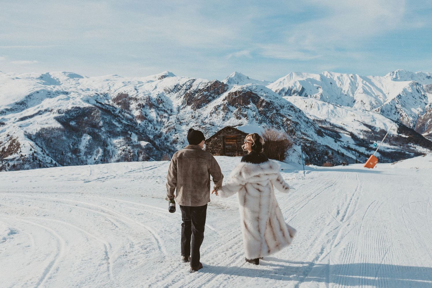 man and woman hold hands walking away on top of mountain