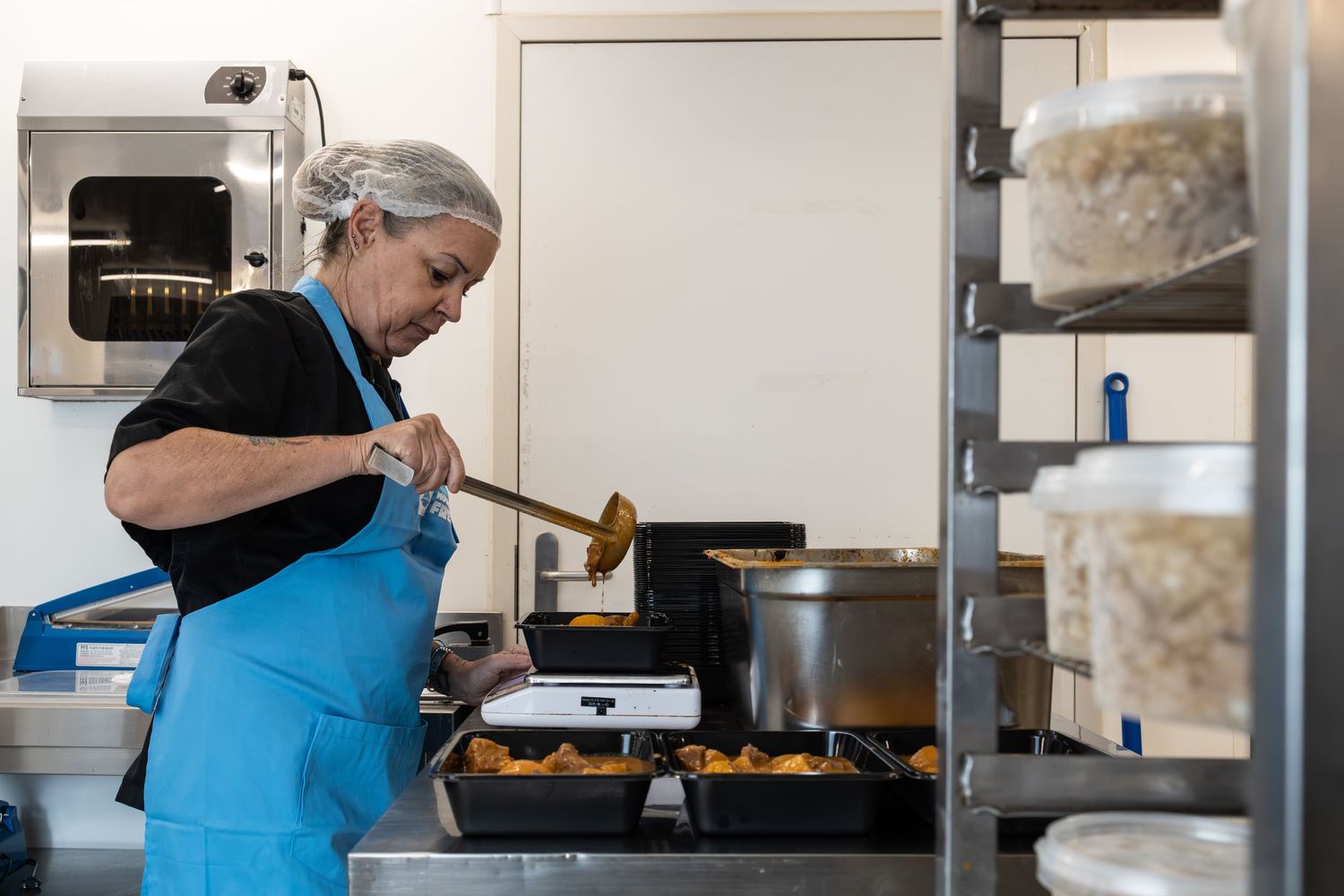chef fills containers with curry in commercial kitchen