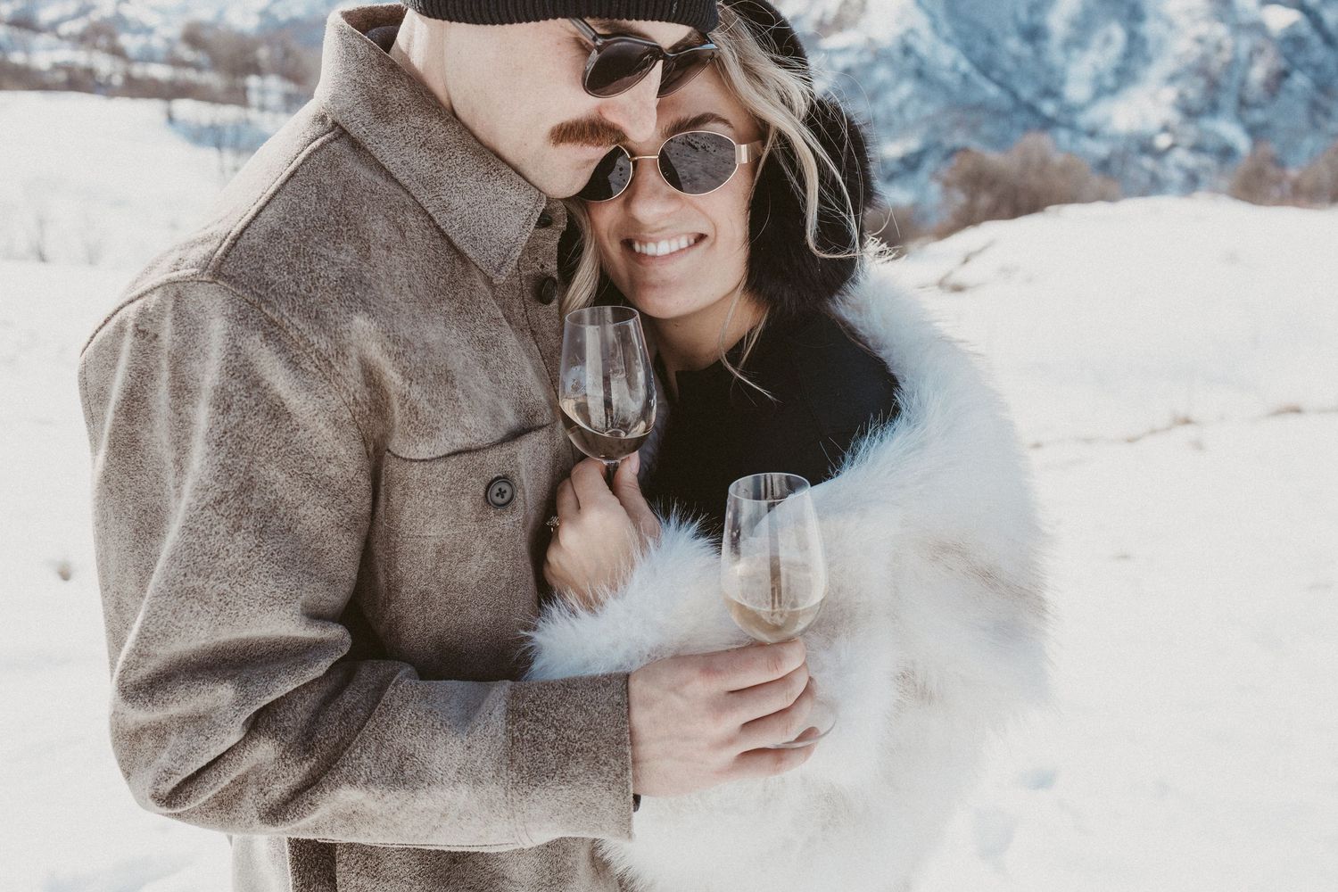 man and woman embrace in mountains after engagement