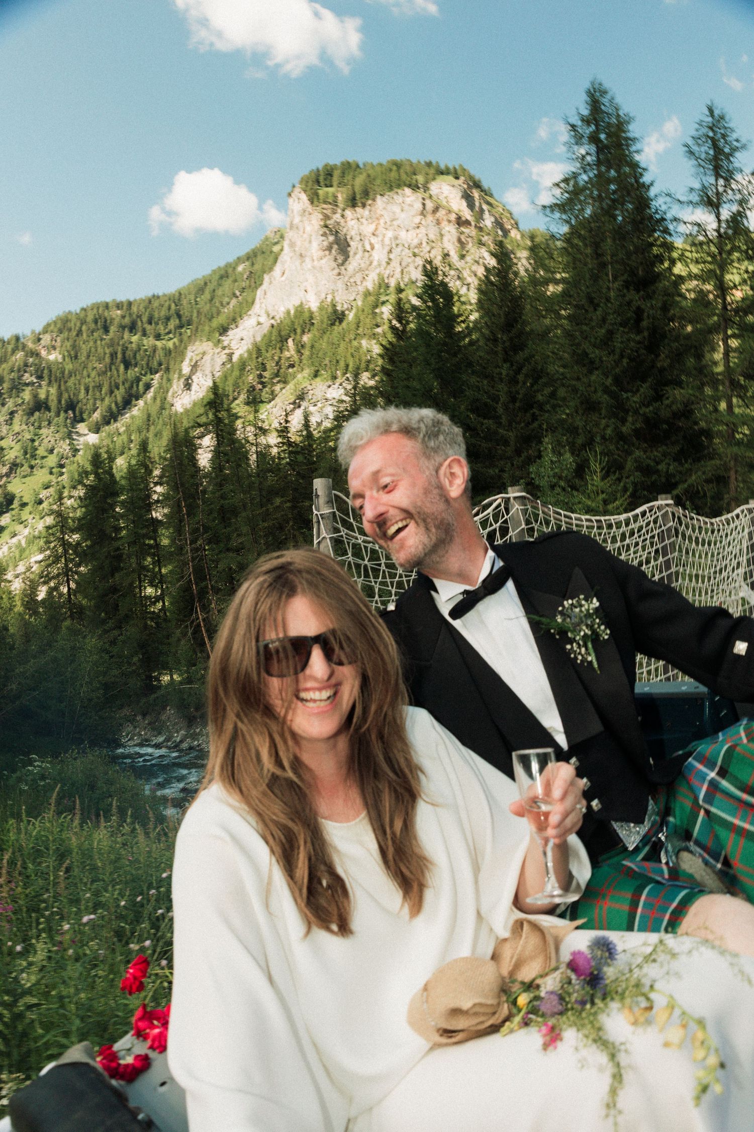newlyweds ride in an open top landrover laughing