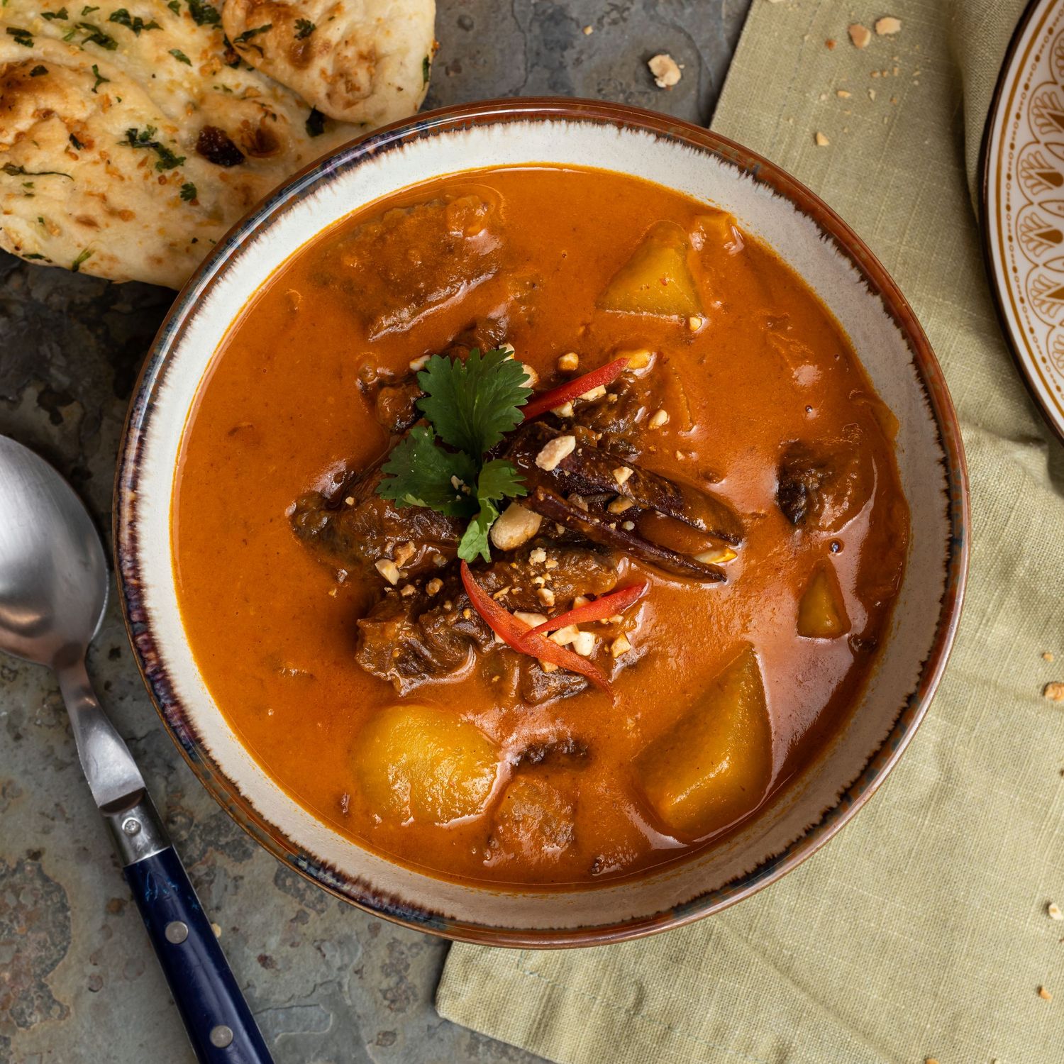 red beef curry and naan bread with spoon ready to eat