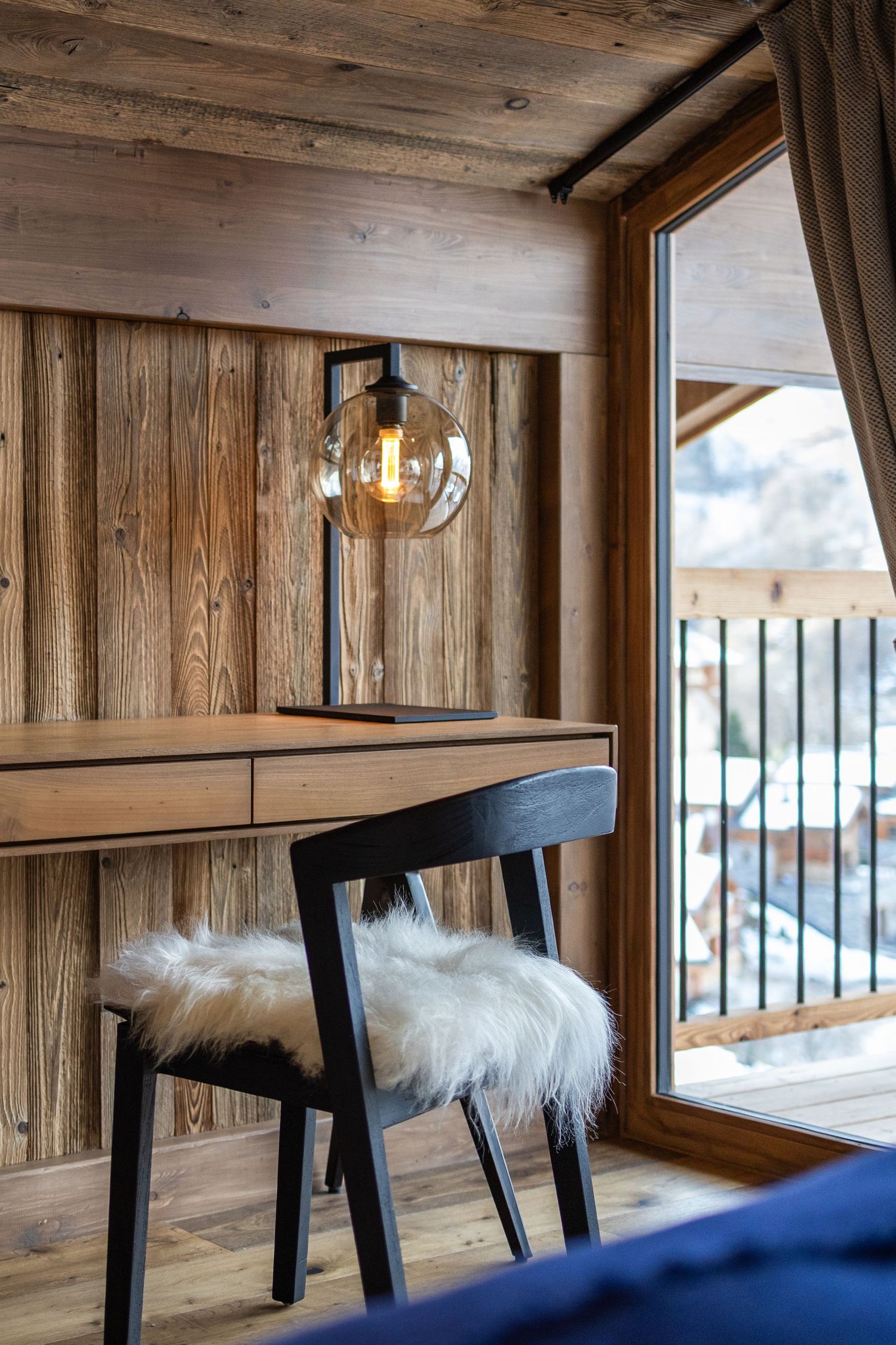 chair with fur seat, in front of table and lamp beside window