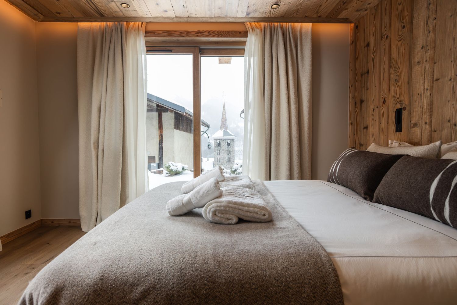 view across bed and bed throw and towels towards door out to snowy village