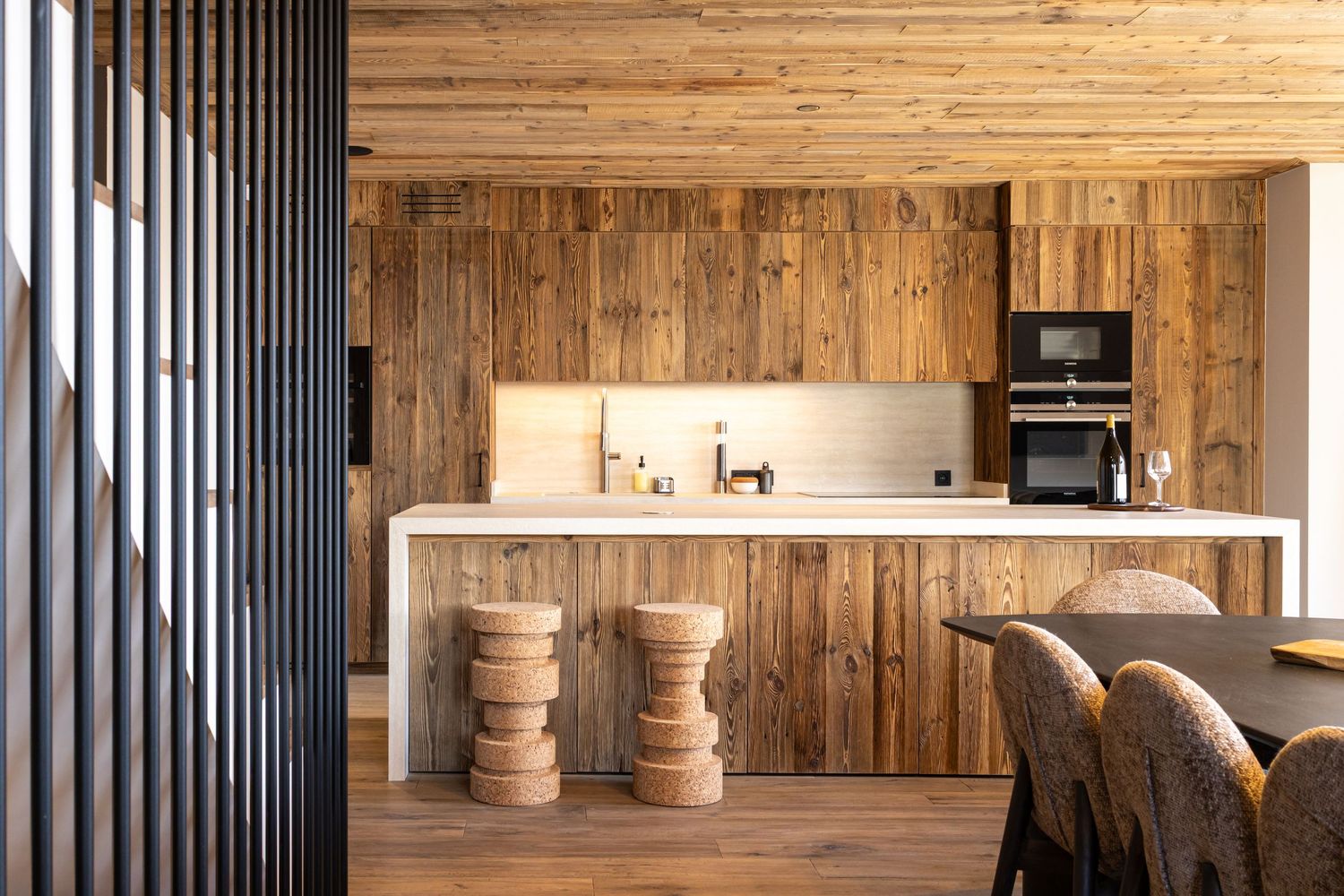 newly built wooden clad contemporary kitchen with two stools at centre island