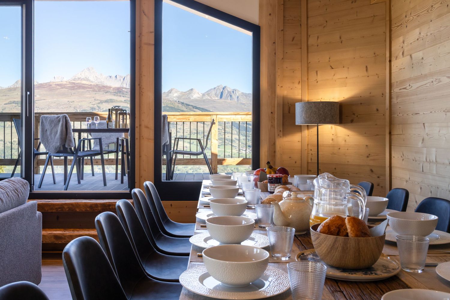 table laid for breakfast with large windows with mountain views behind
