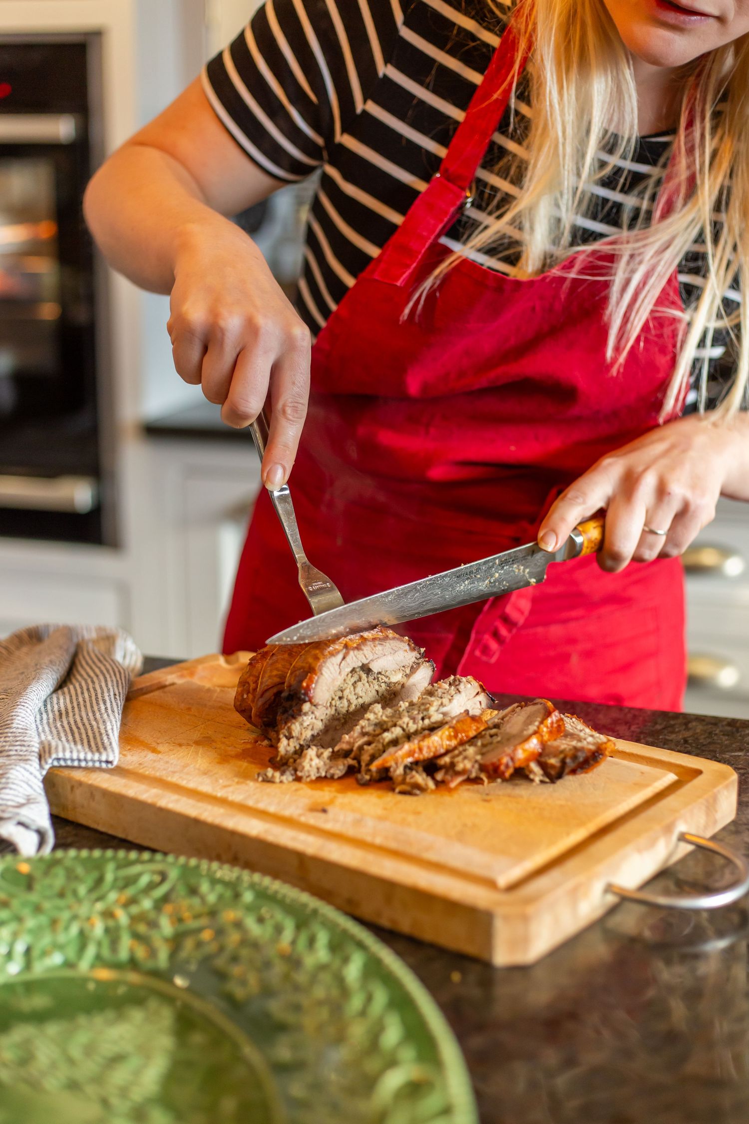 lady with red apron carves Christmas turkey breast