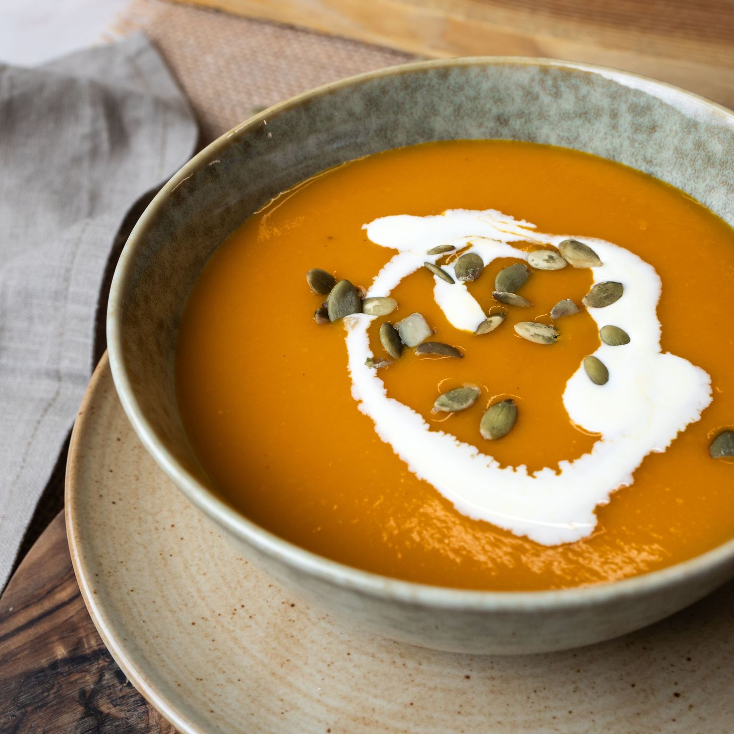 bowl of tomato soup garnished with seeds and cream