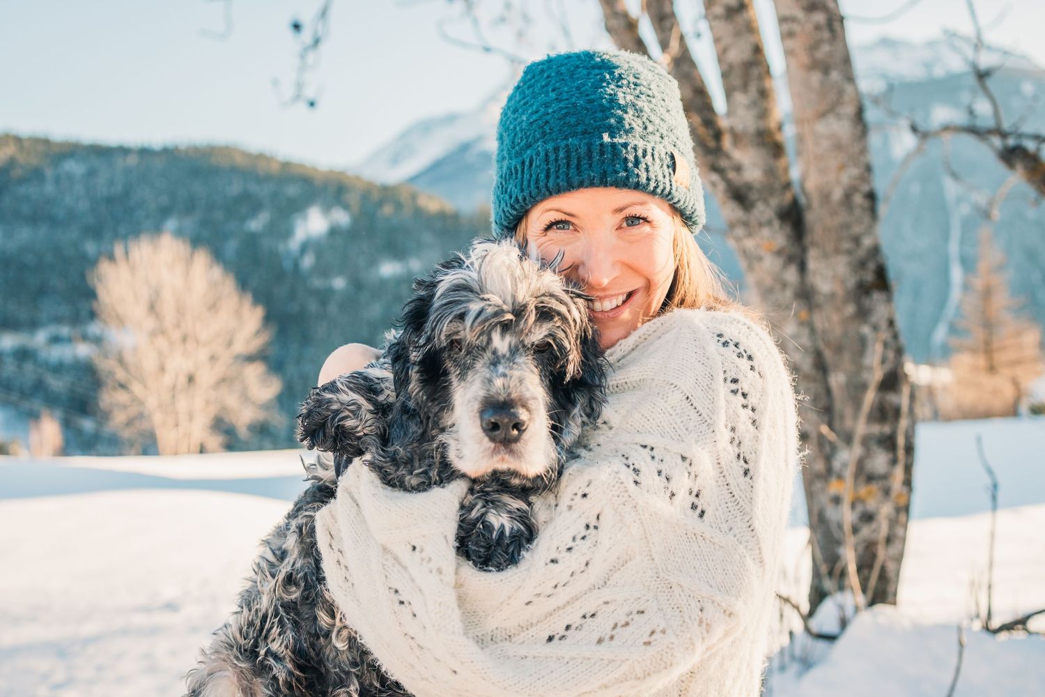 woman cuddles with her elderly dog in the snow