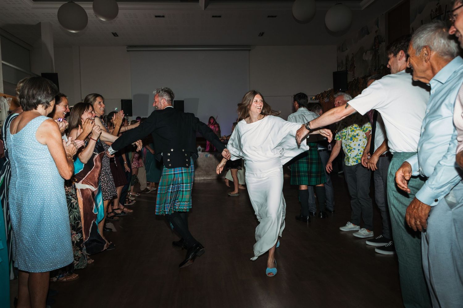 bride and Scottish groom dance the ceilidh at wedding reception