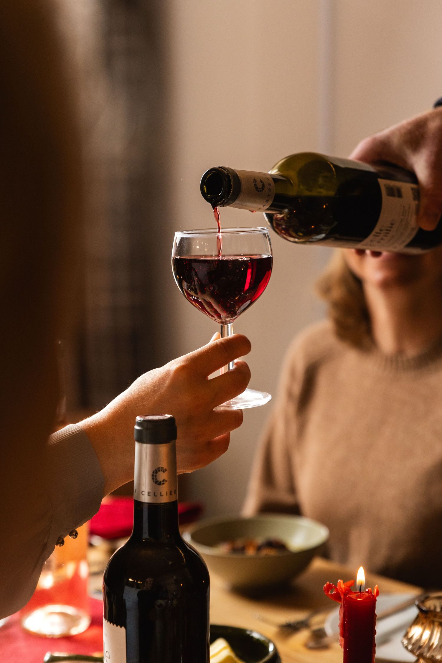 hand pours red wine into glass of friend