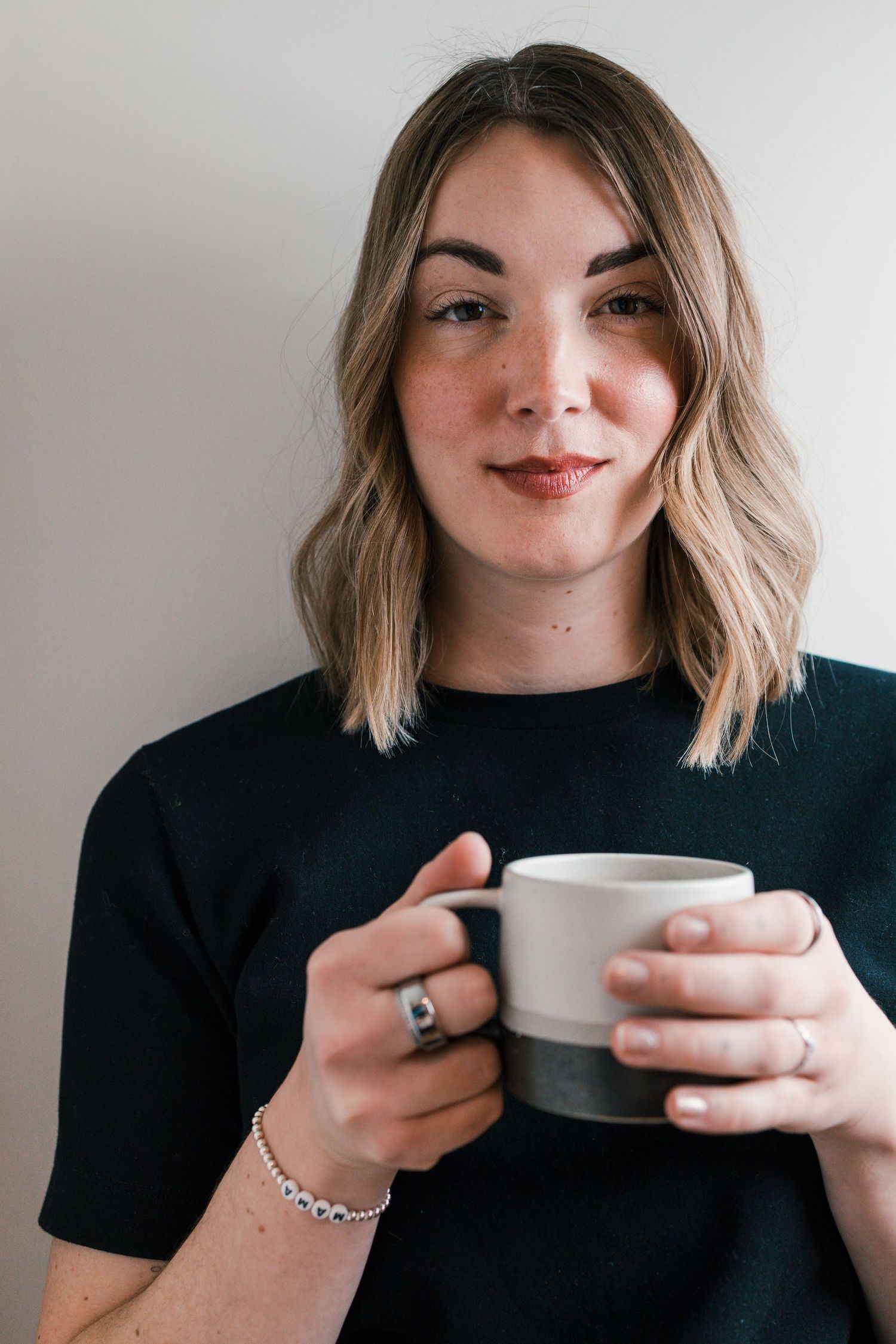 woman with serious expression looking at camera holding a coffee