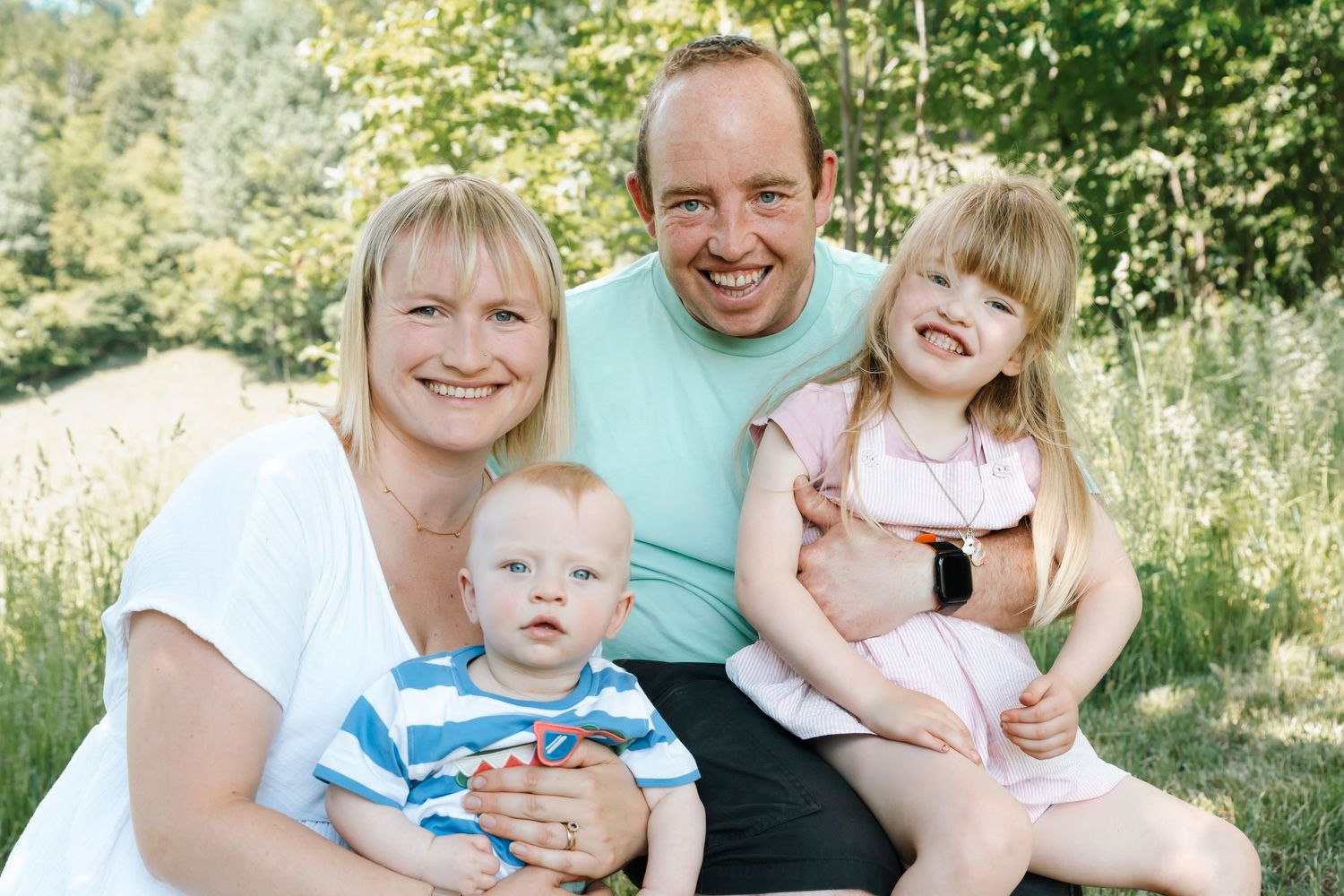 parents with two children smiling in woodland area