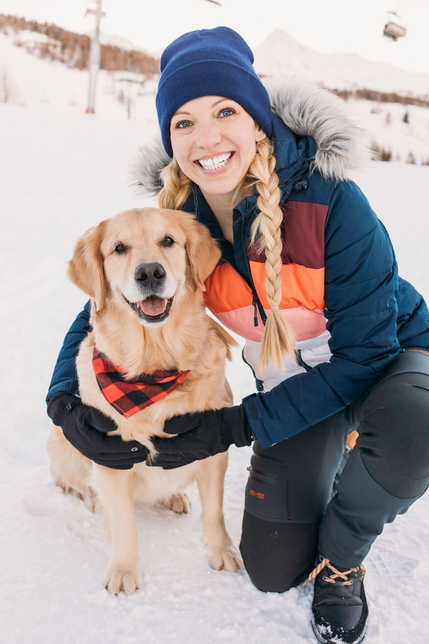 woman on holiday poses for photo with her golden retriever dog on mountain