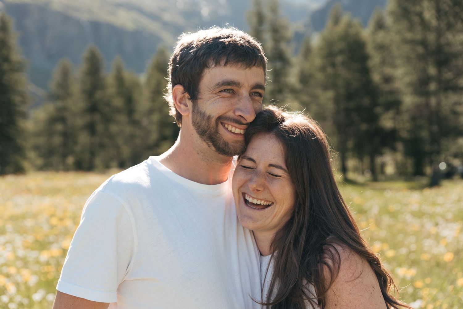 couple laughs happily in a field of flowers