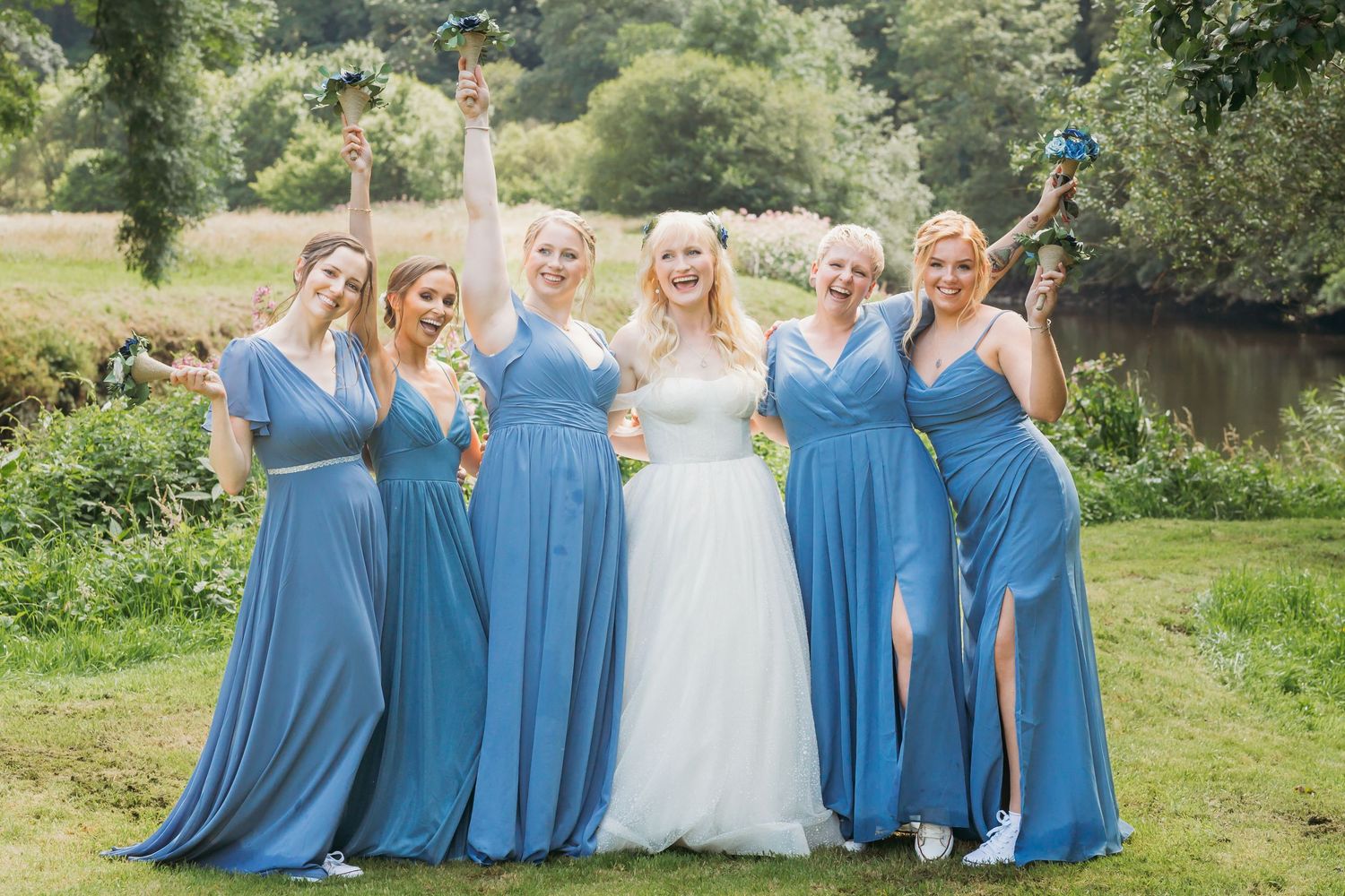 bride and bridesmaids celebrate with bouquets held up in air