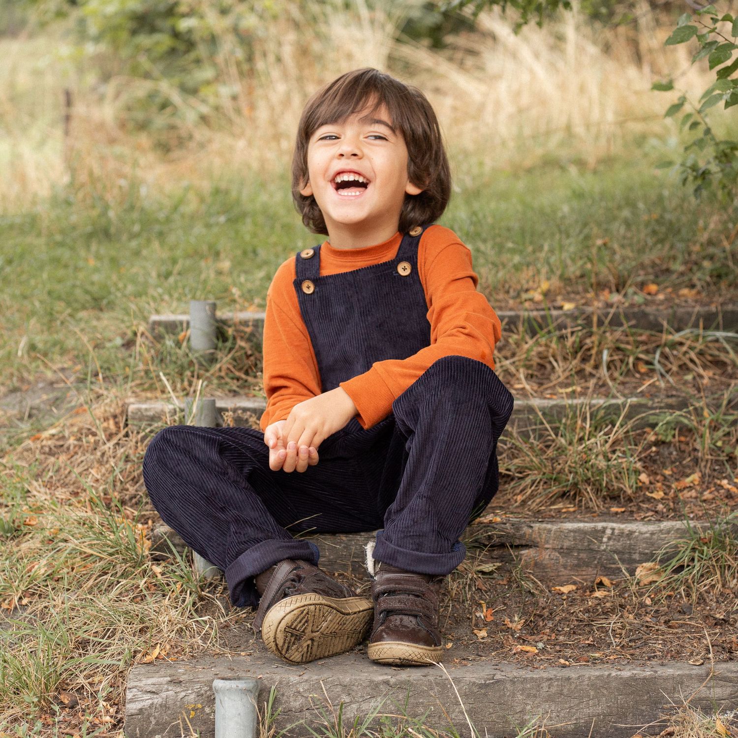 child laughing sat on wooden step in garden