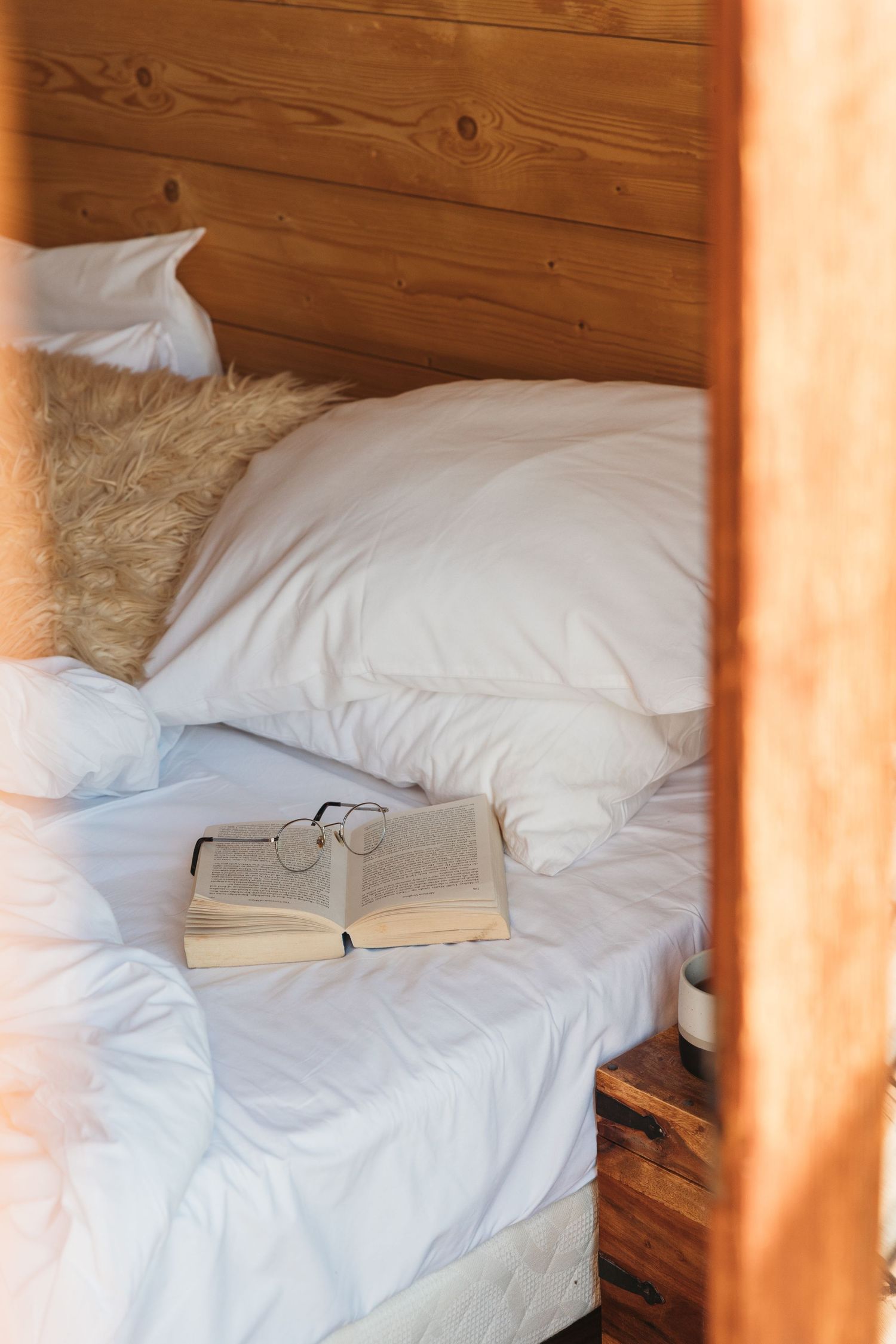 messy bed with book and pair of spectacles