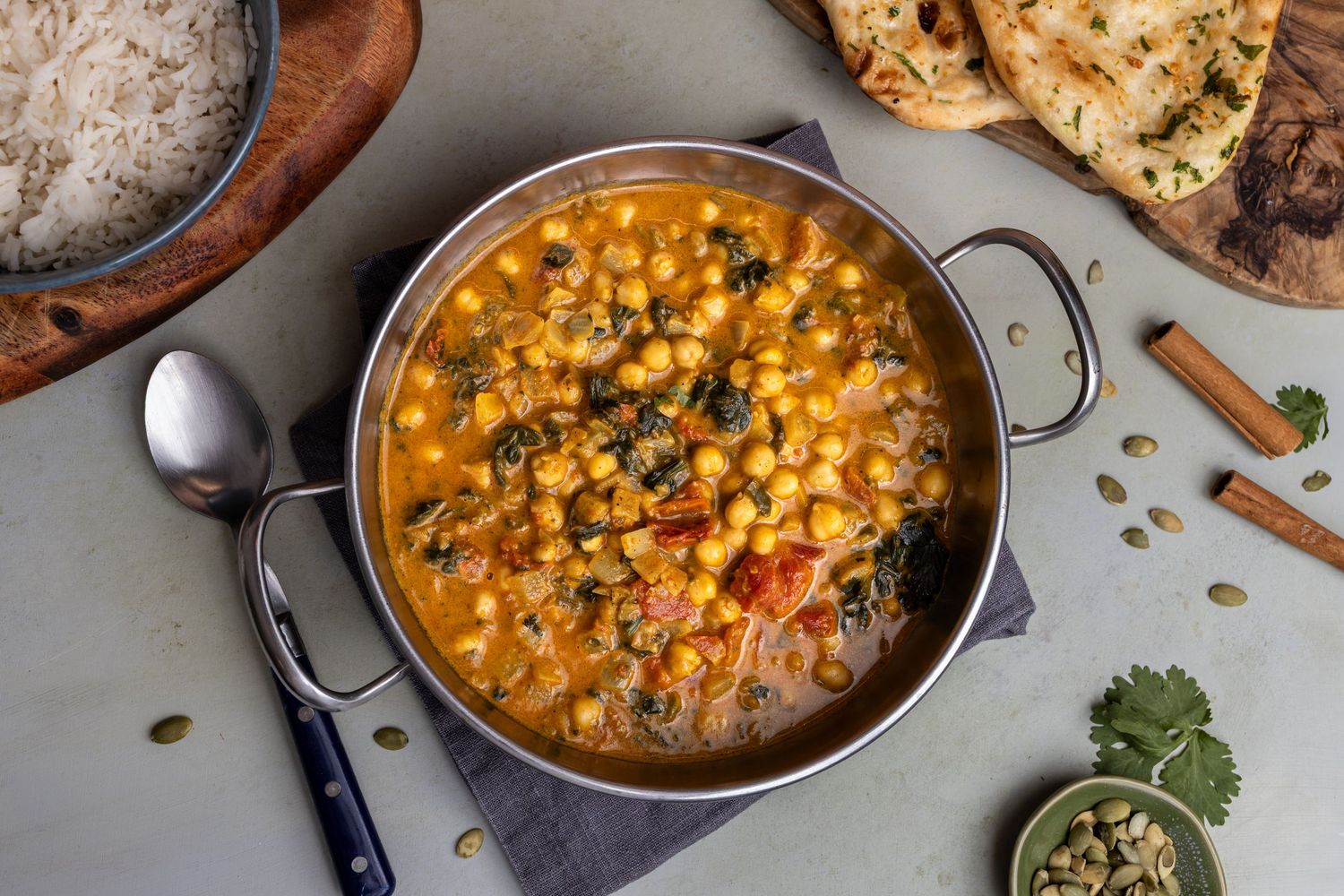 dish of chickpea curry presented with naan breads and rice