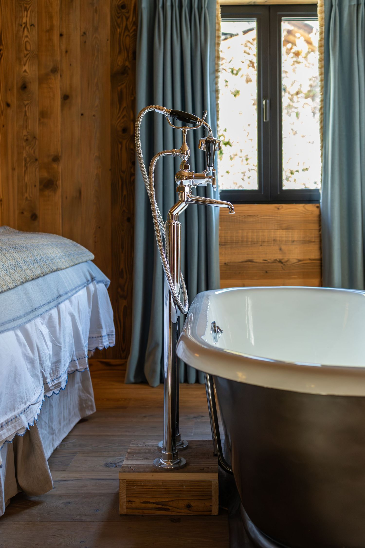 side profile of tap hardware and roll top bath at foot of large double bed