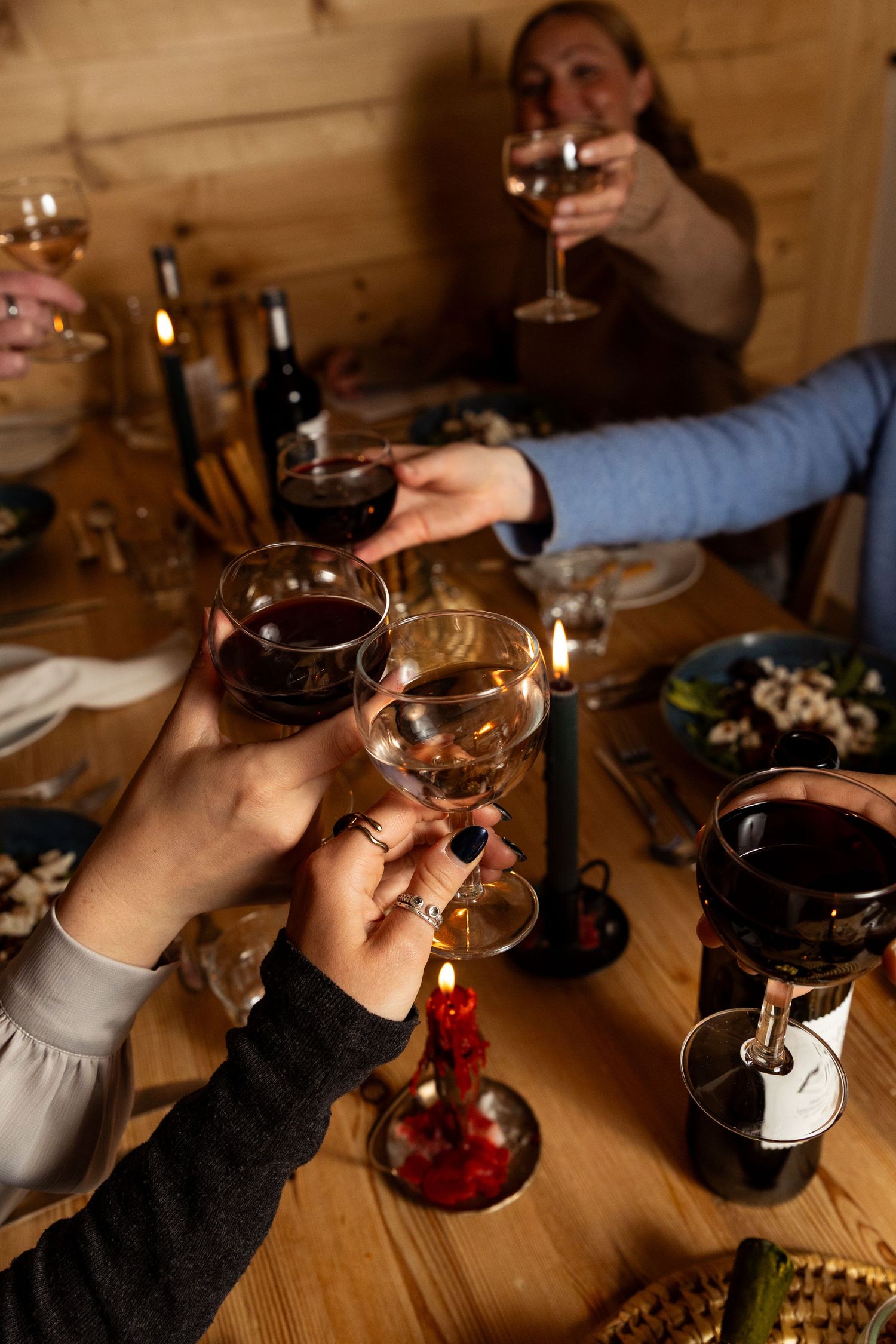 hands cheers above centre of table with multiple glasses of wine