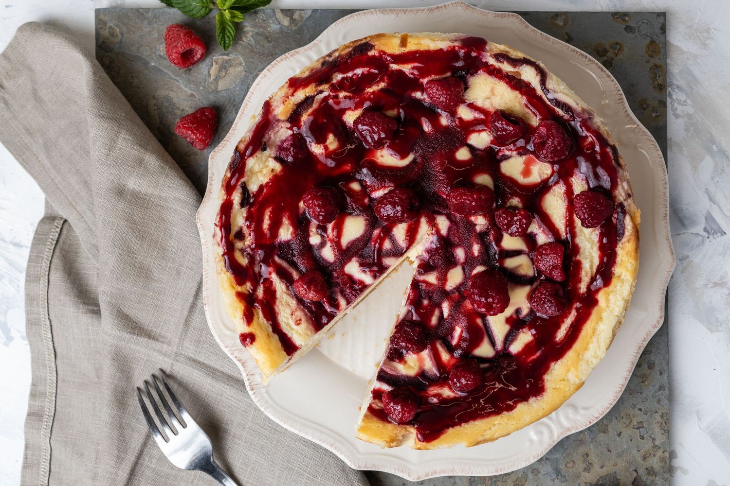 raspberry and white chocolate cheesecake with slice already cut out of it