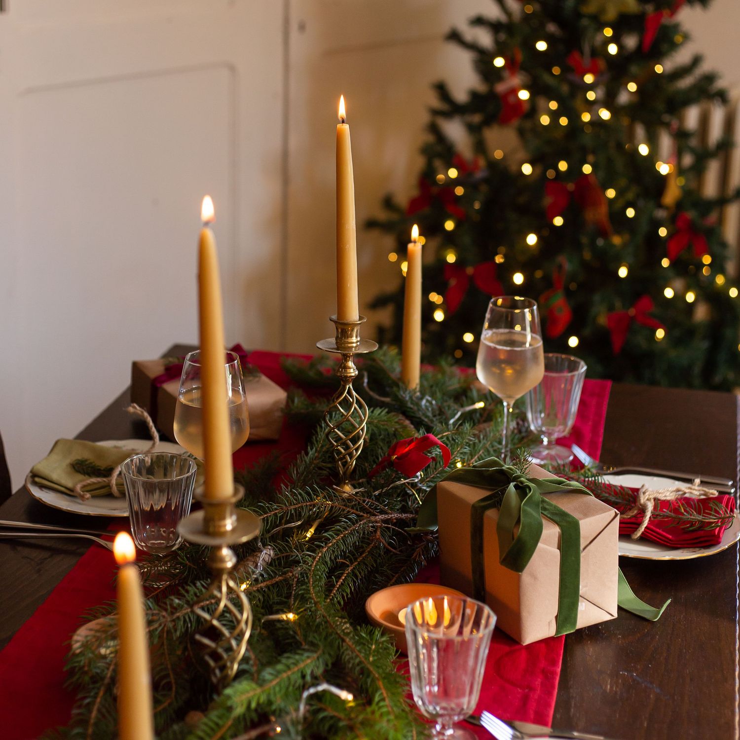 dining table set with candles and Christmas gifts in front of decorated Christmas tree