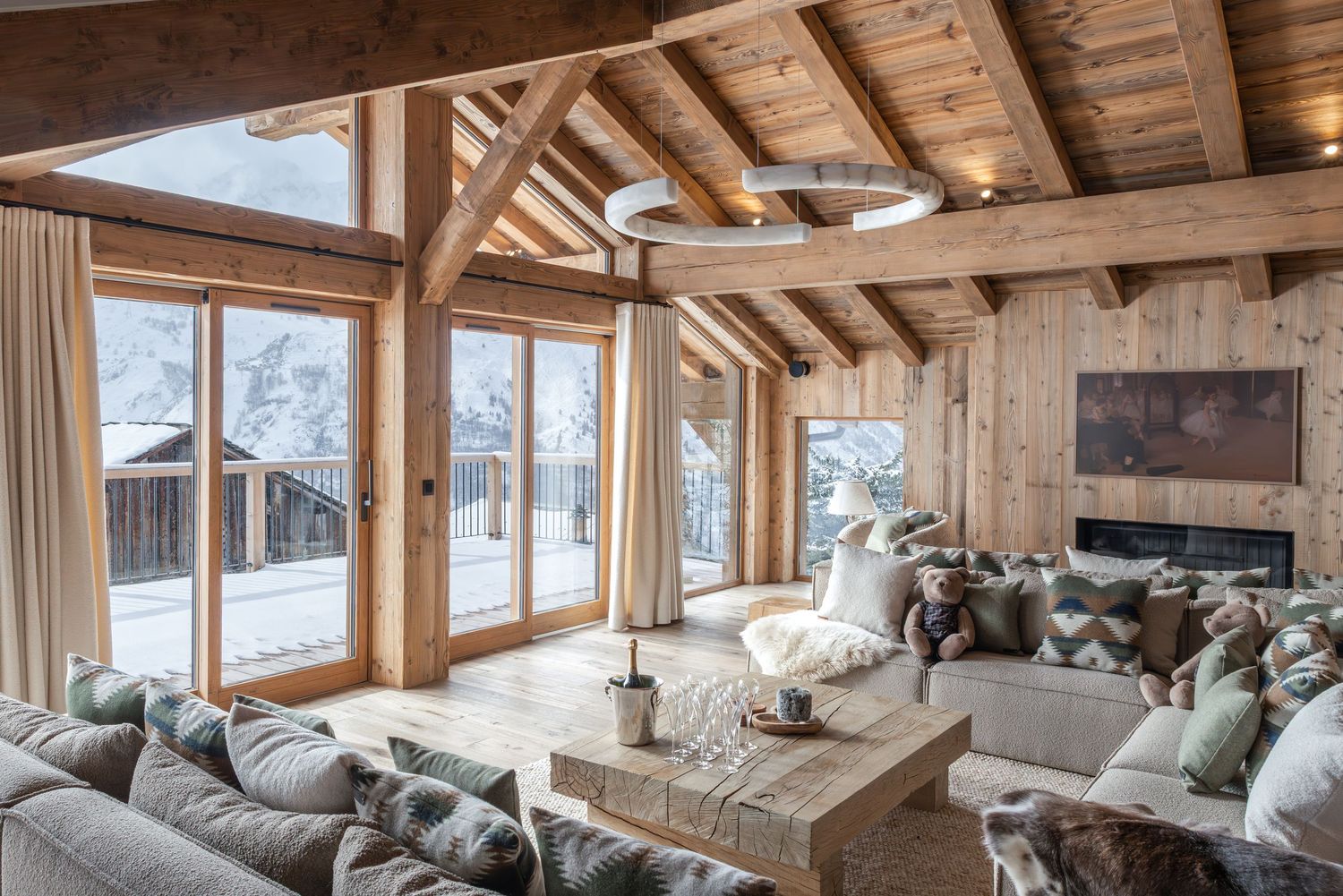 large luxurious living room with floor to ceiling windows looking out onto snowy mountains