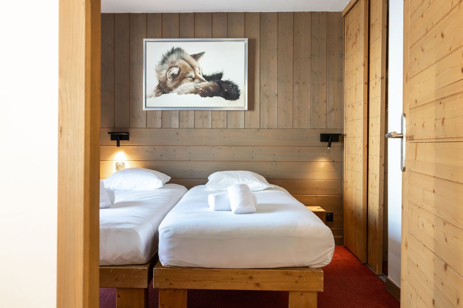 twin beds fully made with towels laid on top of them for ski holiday guests