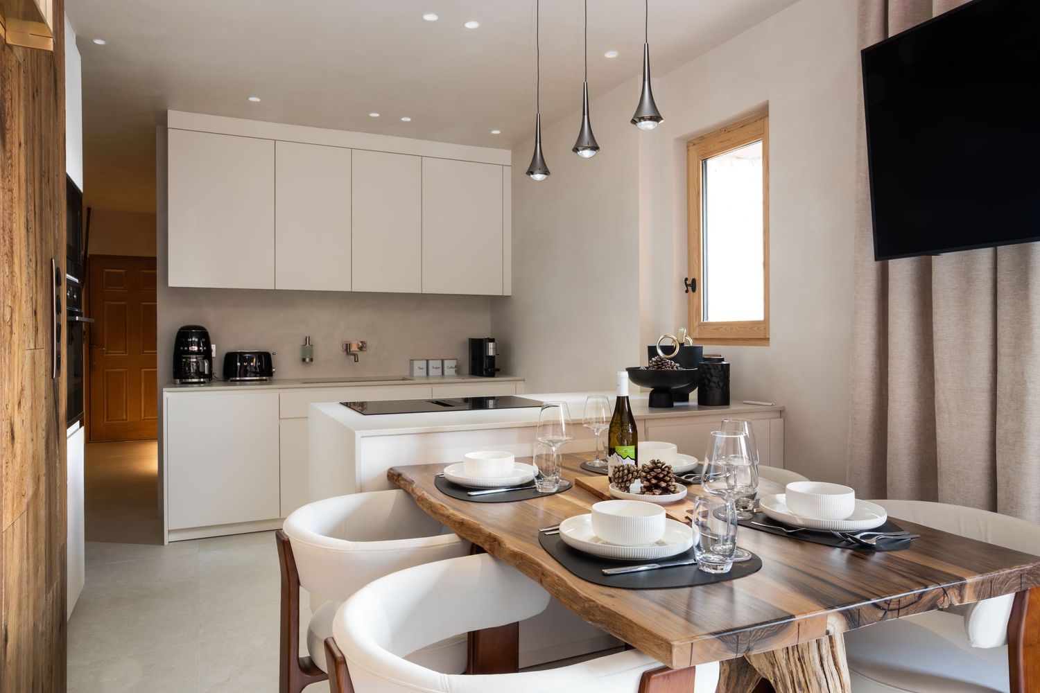 white kitchen and dining area with dining table laid up for meal