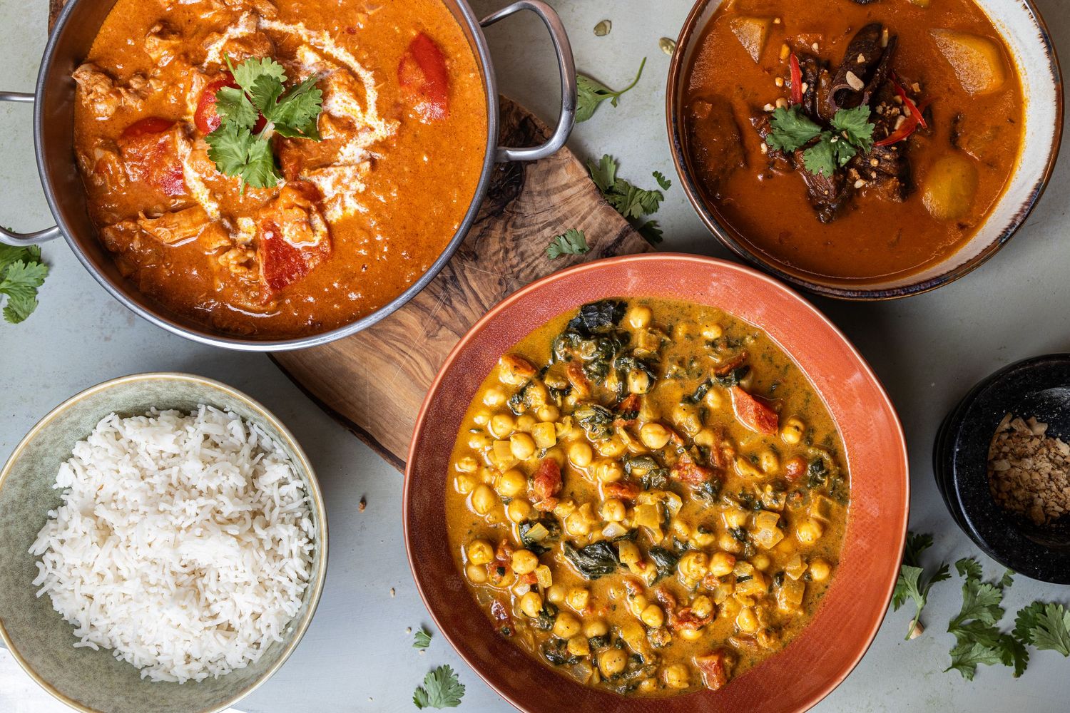 selection of curries laid on wooden board with rich and coriander