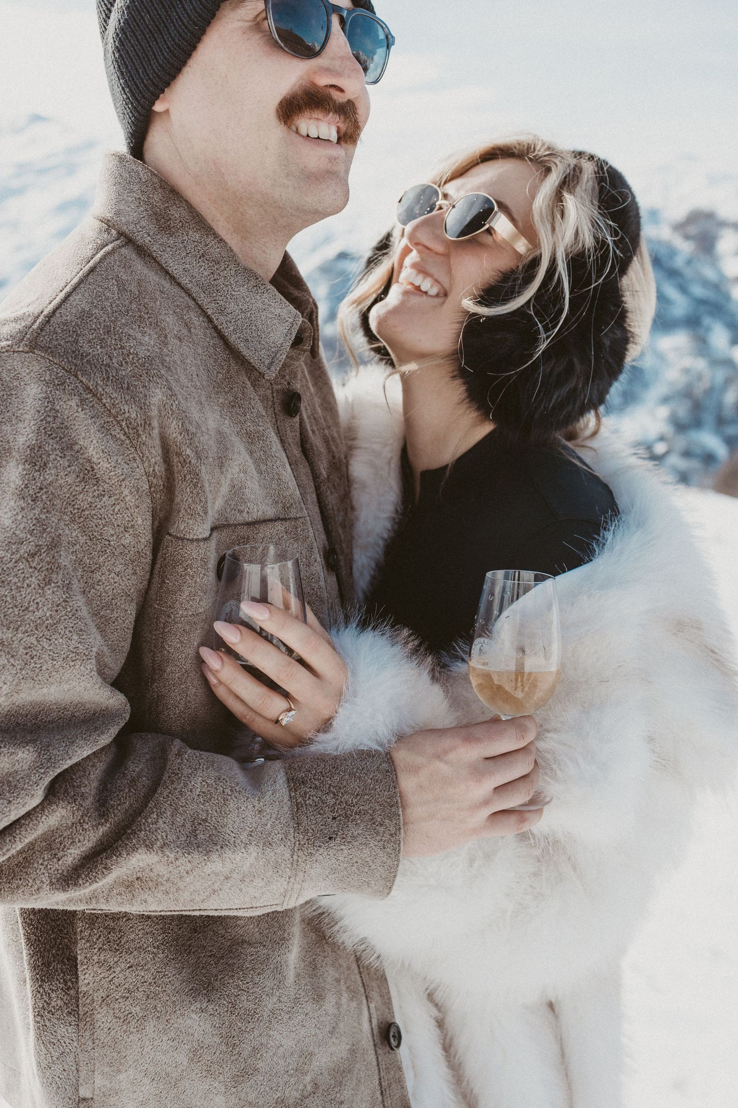 man and woman embrace while holding champagne
