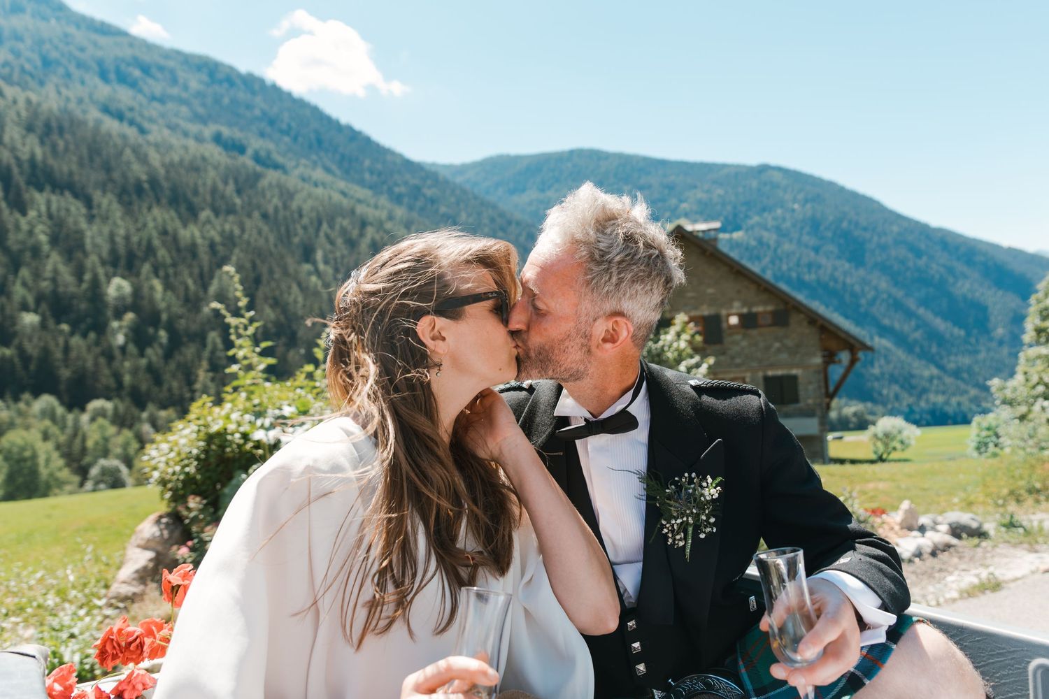 bride and groom kiss in back of open top Land Rover while driving in French alps